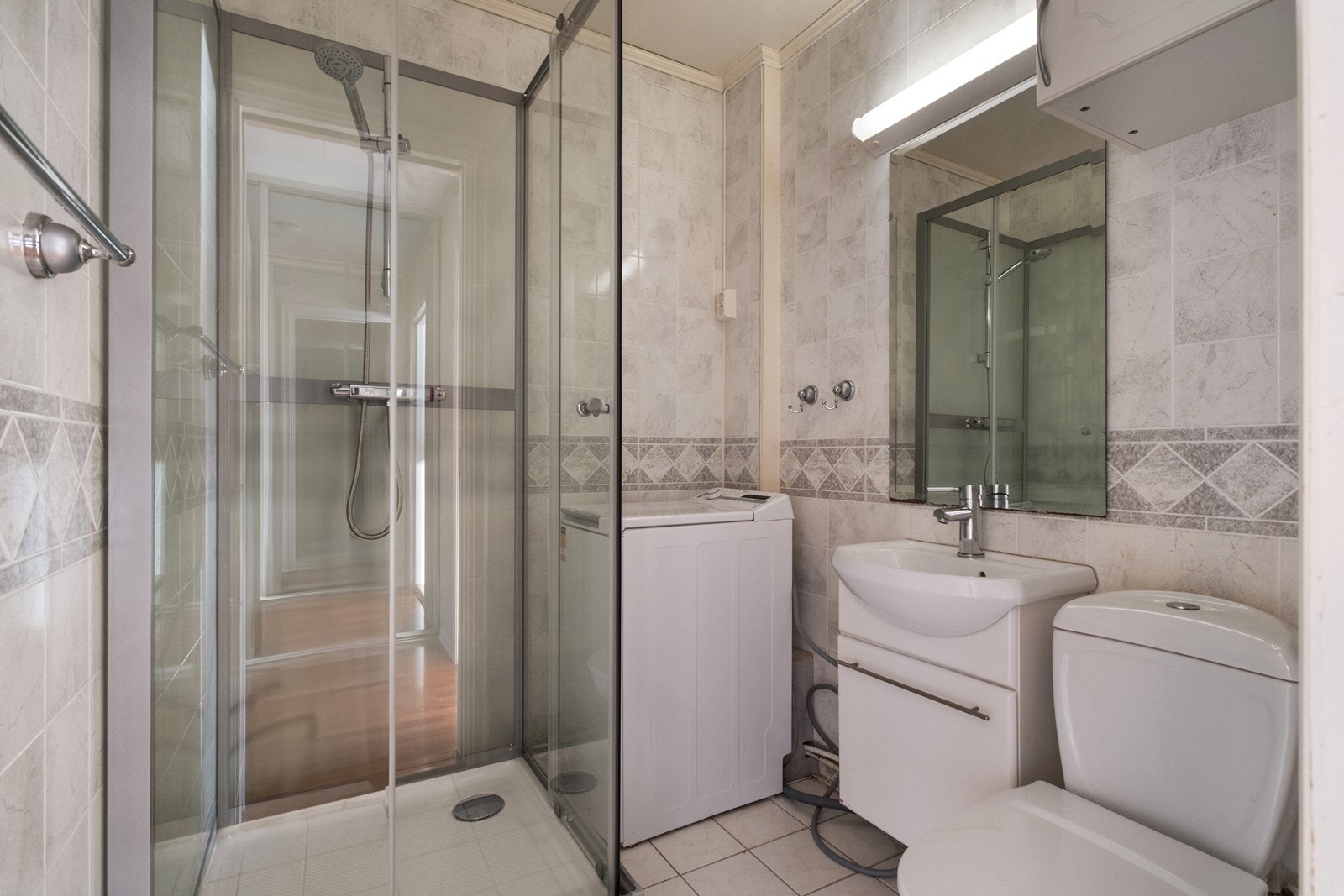 Videre har badet servant med underskap, speil med overlys og gulvmontert toalett. Galleribilde