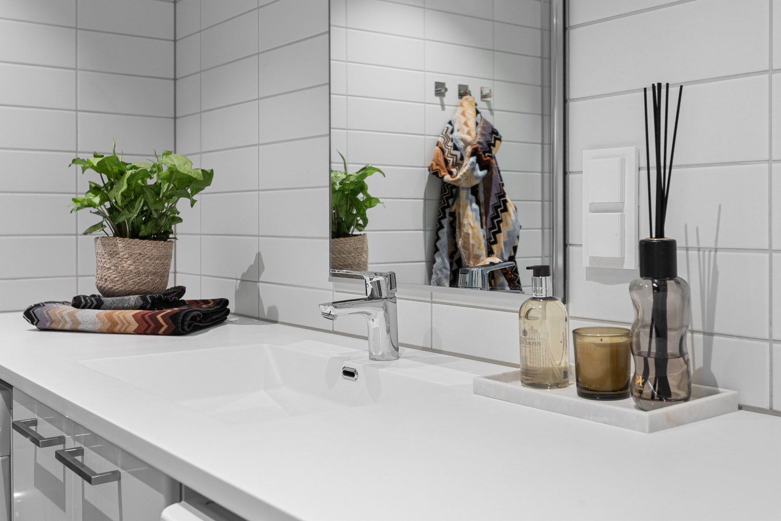 Rommet har god plass til både vaskemaskin og tørketrommel, og er innredet med en heldekkende servant med tilhørende underskap og servantplate som gir rikelig med benkeplass. Galleribilde