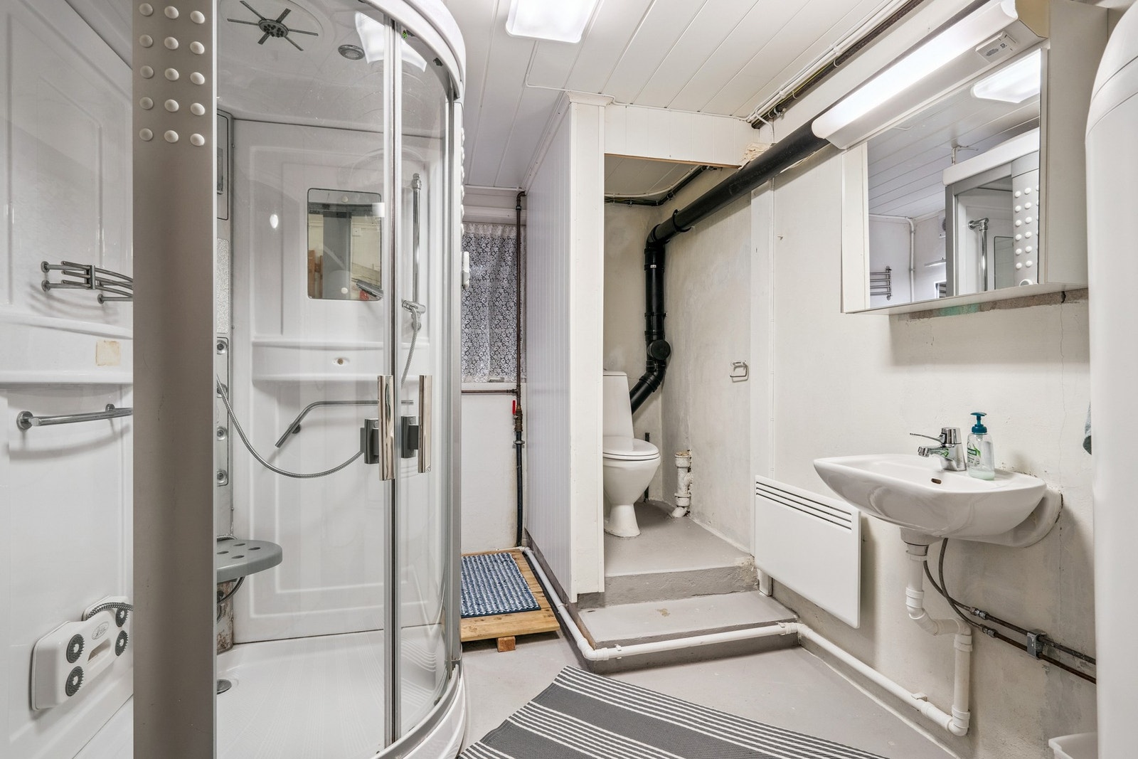 Bad i kjeller med dusjkabinett, toalett og vask. Galleribilde