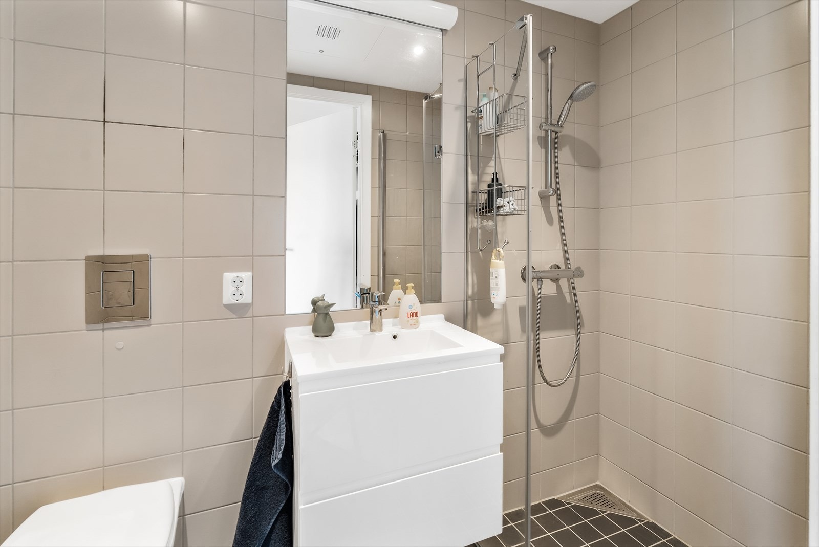 Vegg i vegg med bad/vaskerom er det et mindre bad med dusjhjørne, vegghengt wc og lys baderomsinnredning. Varmekabler i gulv. Galleribilde