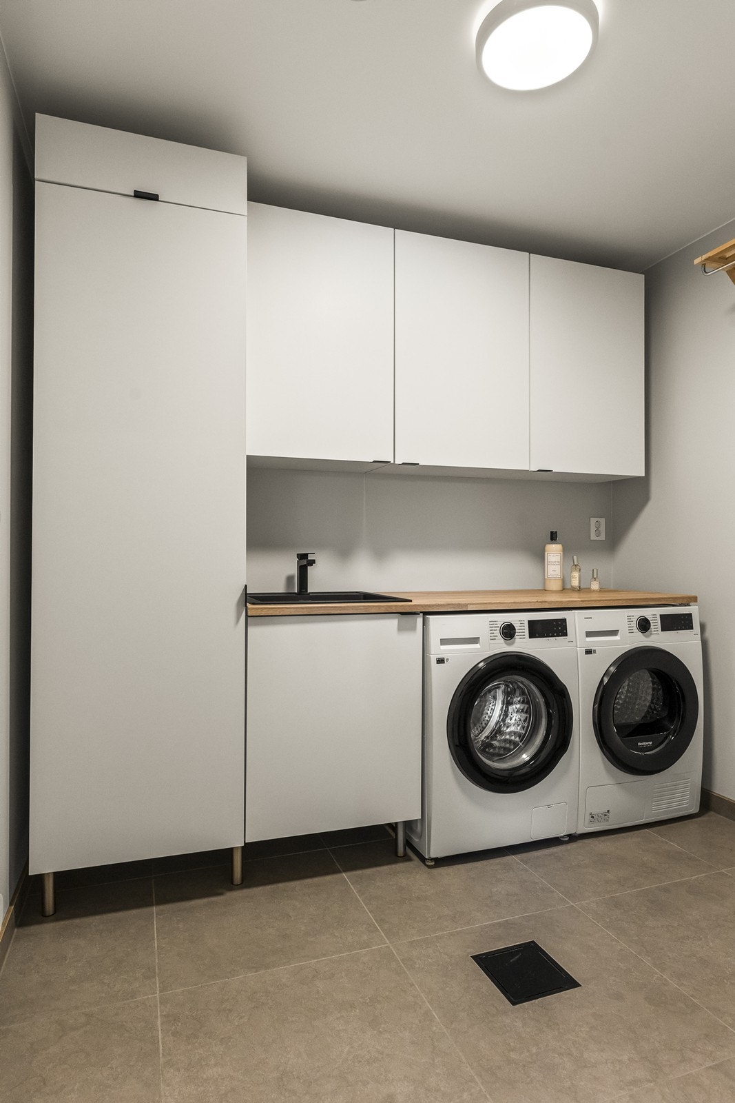 Vaskerom/teknisk rom 60 x 60 fliser med underliggende varmekabler på gulv og med vaskeromsinnredning fra Mesterkjøkken Galleribilde