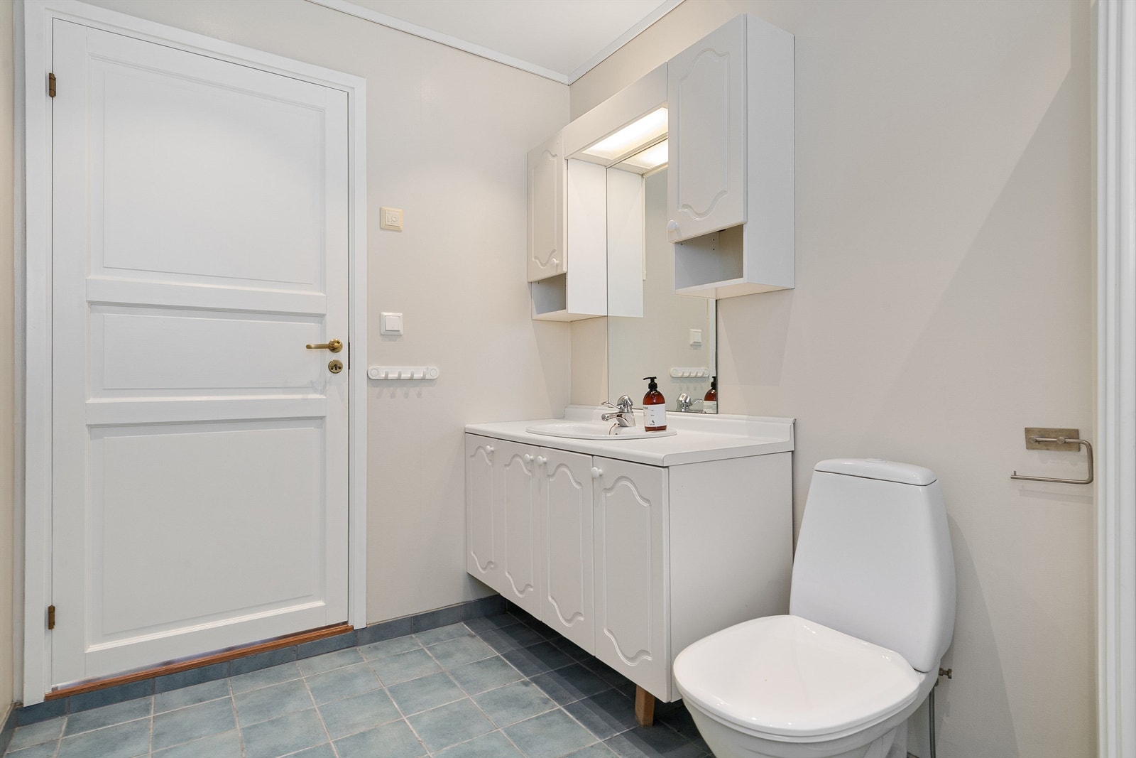 Badet er utstyrt med baderomsinnredning, gulvmontert toalett, dusjhjørne med buede dusjvegger og opplegg for vaskemaskin Galleribilde