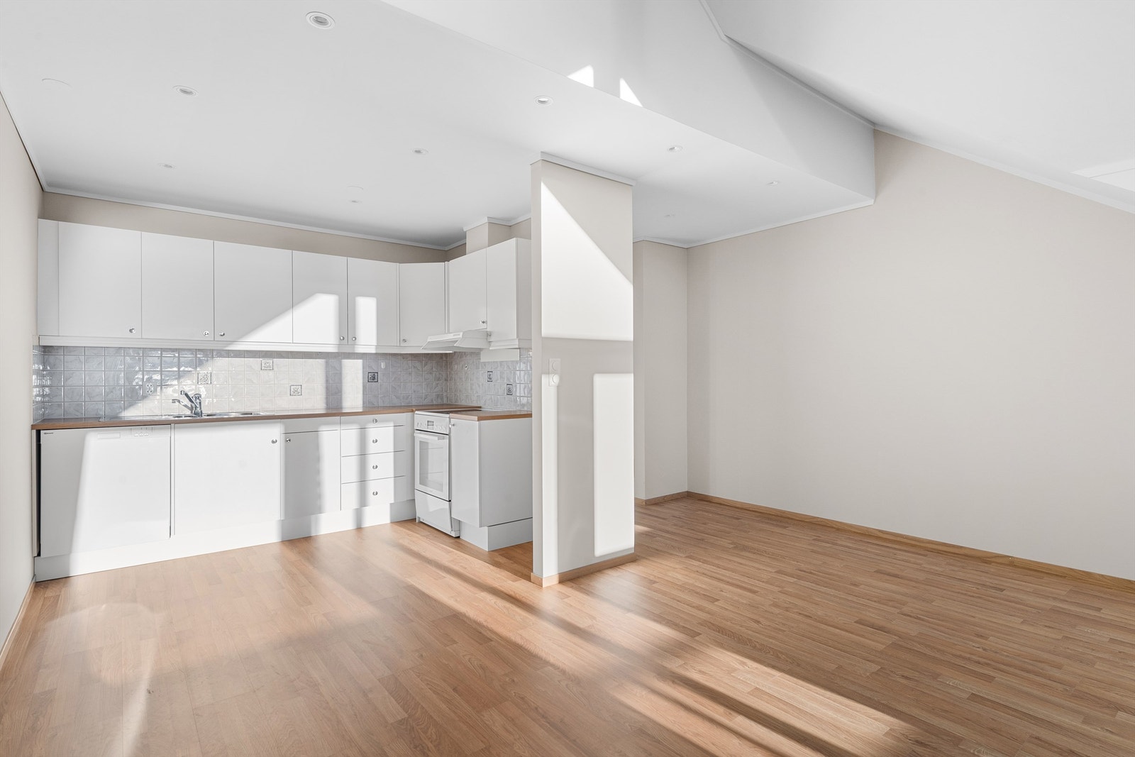 Lys og trivelig stue/kjøkken med glatte hvite tak og delvis innfelte spotlights Galleribilde