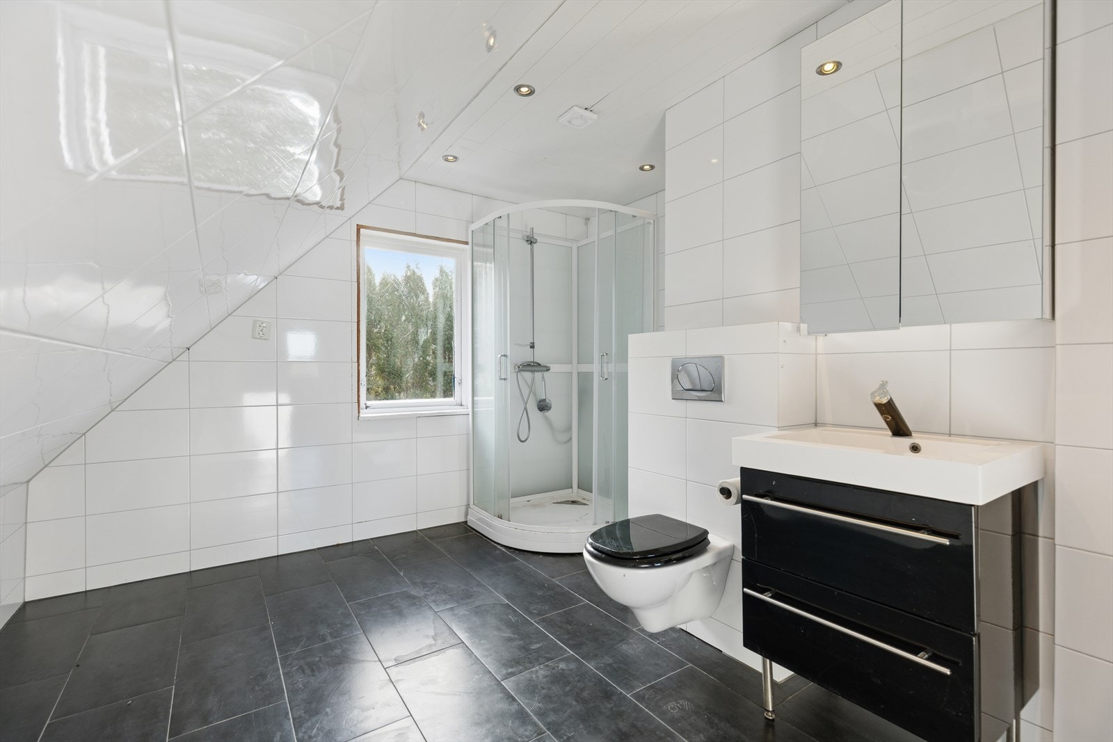 Stort baderom utstyrt med vegghengt toalett, dusjkabinett og servant med underskap. Galleribilde