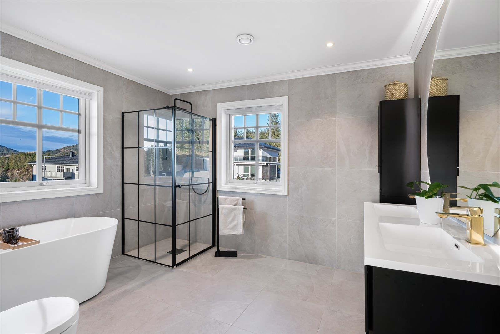 Et lyst og moderne bad med lyse fliser på vegger og gulv. Galleribilde