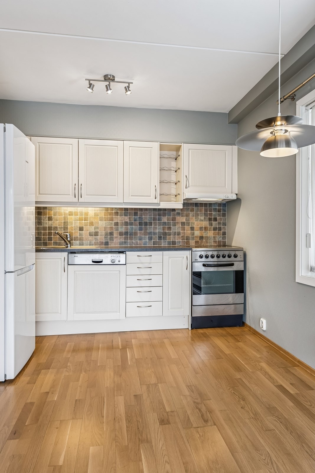 Kjøkkenet har en profilert, L-formet innredning med laminat benkeplate. Galleribilde