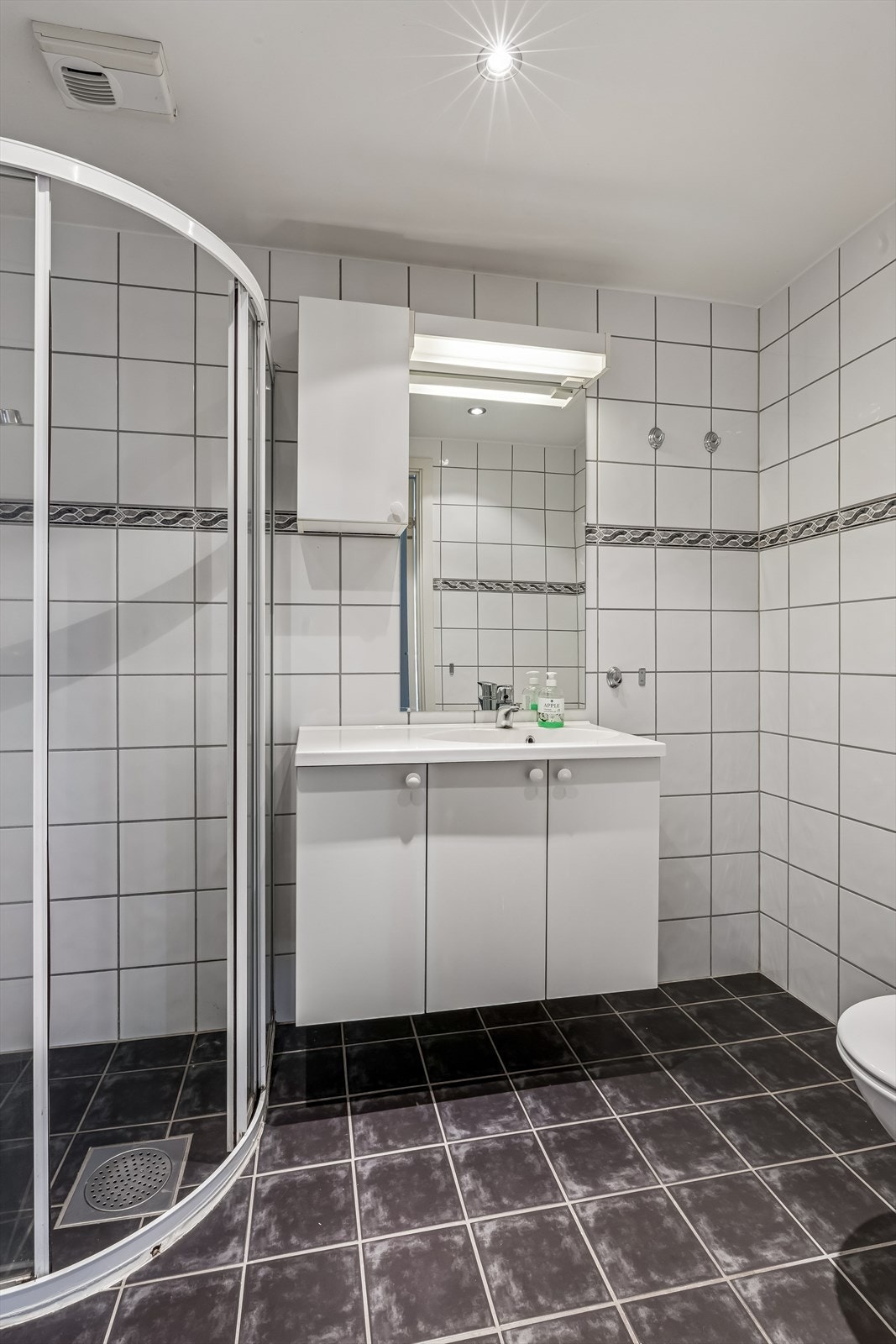 Badet er helfliset med lyse fliser på vegg og mørkere på gulv. Galleribilde