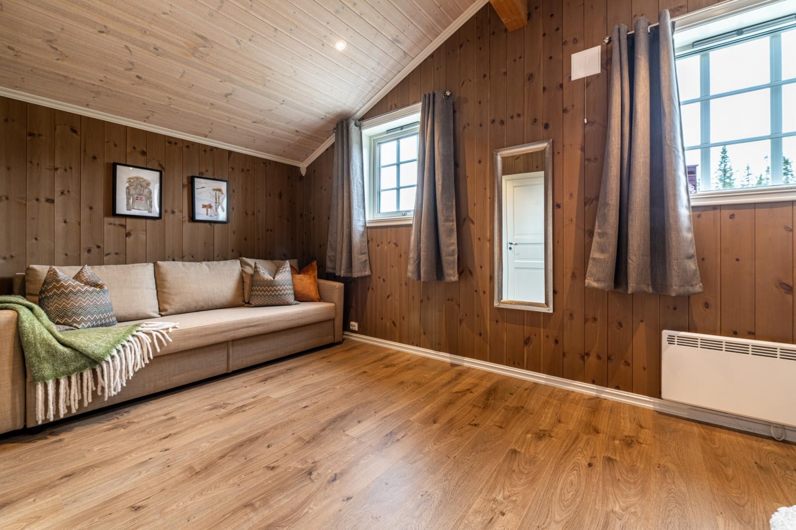 Lyst rom med plass til sofa og store vinduer som slipper inn mye dagslys. Galleribilde