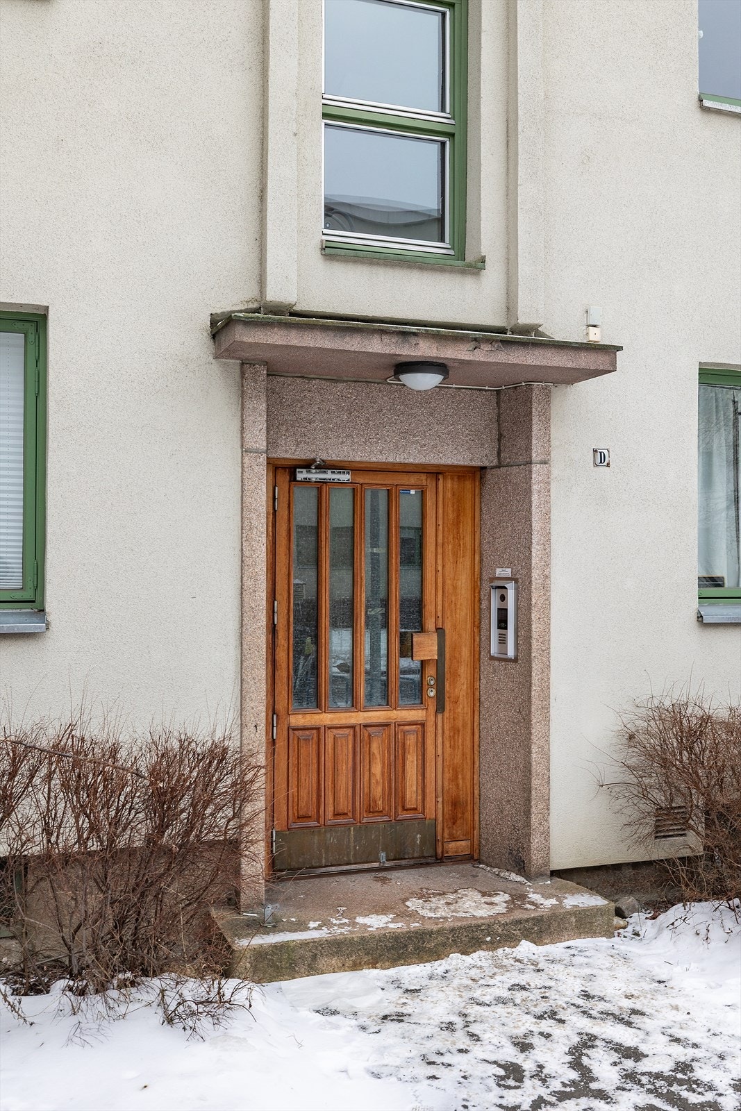 Inngangspartiet har en solid tredør med overlys, omkranset av steinramme. Galleribilde