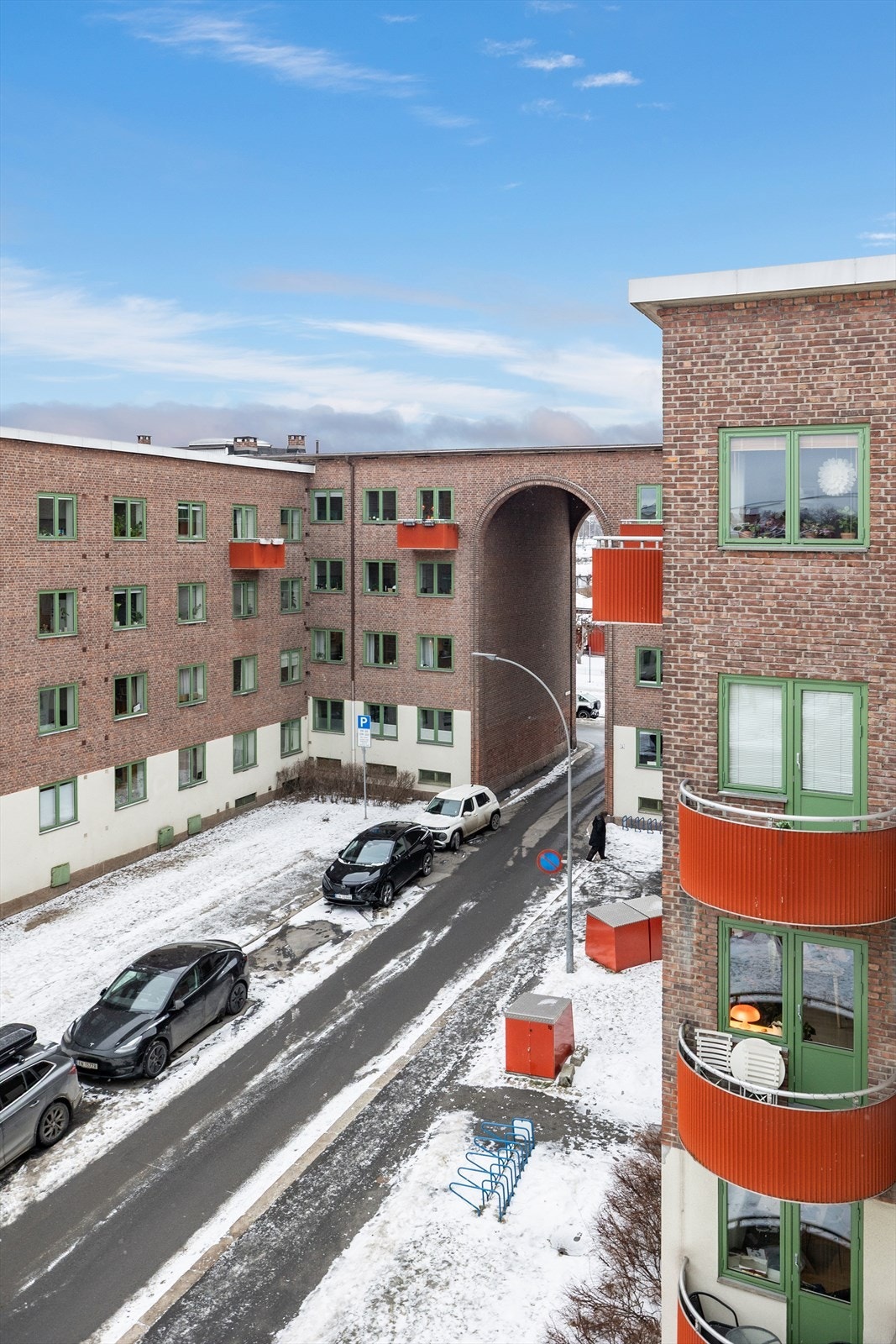 Bygningen har teglfasade med grønne vinduskarmer og røde balkonger. Galleribilde