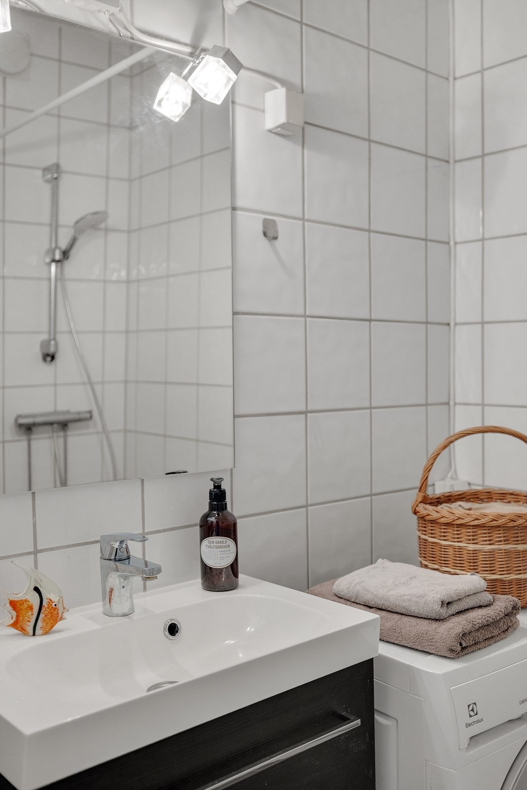 Innredet med et stilrent servantskap med mørke, glatte fronter og en heldekkende servant med speil og belysning over. Galleribilde