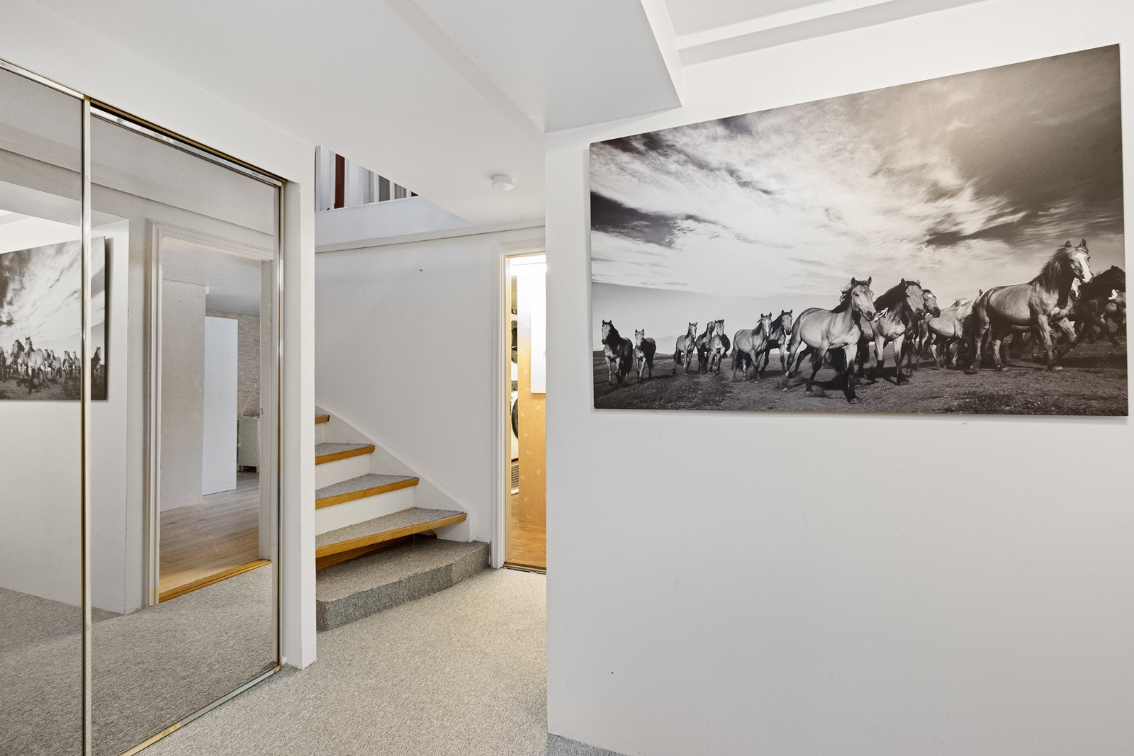 I kjelleren er det en smart skyvedørsgarderobe med speilfronter under trappen. Galleribilde