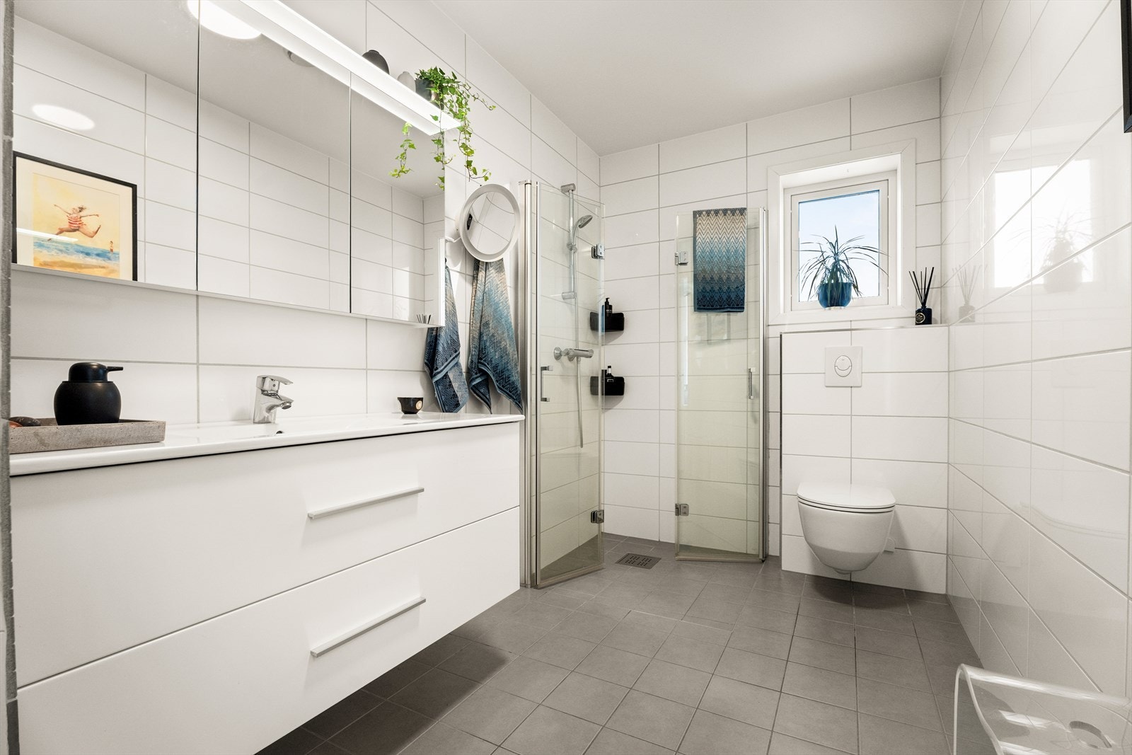 Lekkert bad med servantinnredning, dusjhjørne med glassdører og vegghengt toalett. Galleribilde