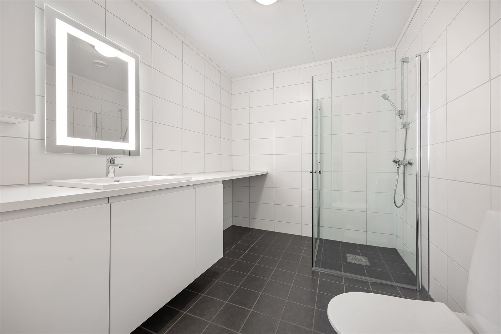 Badet er helfliset og utstyrt med dusjhjørne med innfellbare vegger. Galleribilde