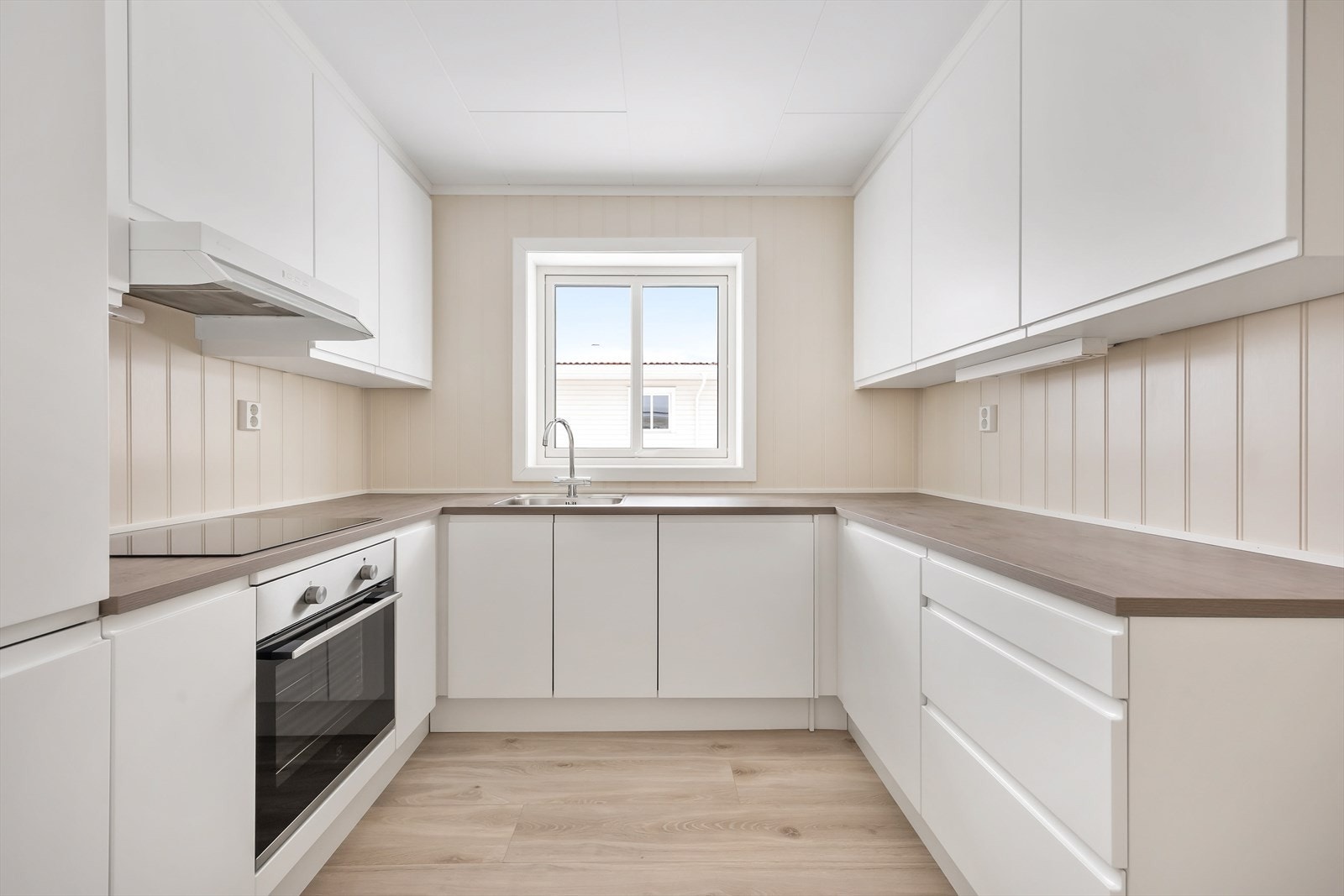 Kjøkkenet har en praktisk U-form med glatte fronter og integrerte hvitevarer. Galleribilde