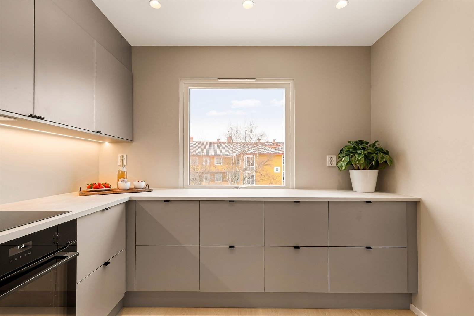 Kjøkkenløsningen er moderne og tidsriktig, med glatte fronter, laminert benkeplate og elegante, sorte detaljer. Et stort vindu over kjøkkenbenken sørger for rikelig dagslys og en lys, åpen atmosfære. Galleribilde