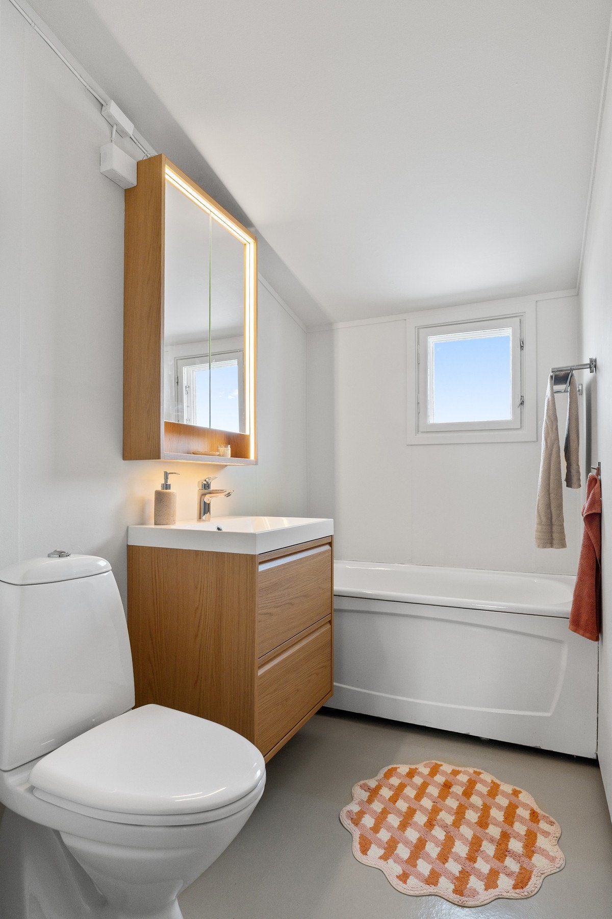 Lyst og funksjonelt med badekar, toalett og servant. Vindu gir dagslys og naturlig ventilasjon Galleribilde