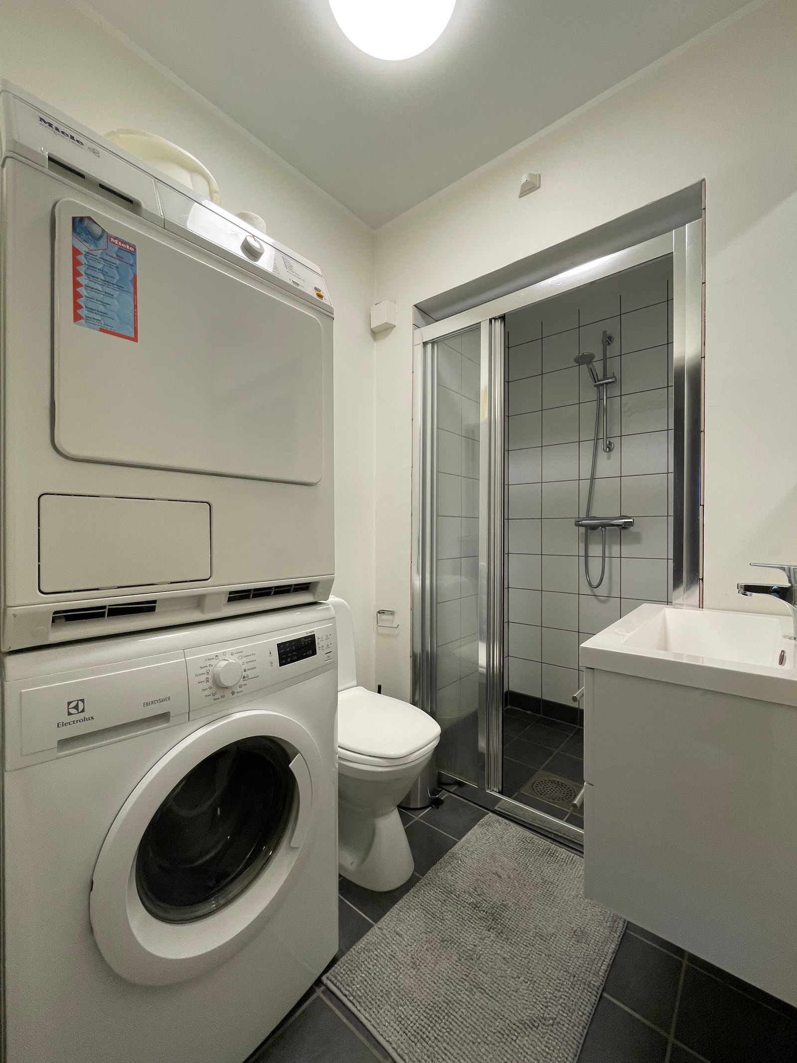 Stilrent bad med dusjhjørnet, servant med underskap og toalett. Vaskemaskin og tørketrommel medfølger. Galleribilde