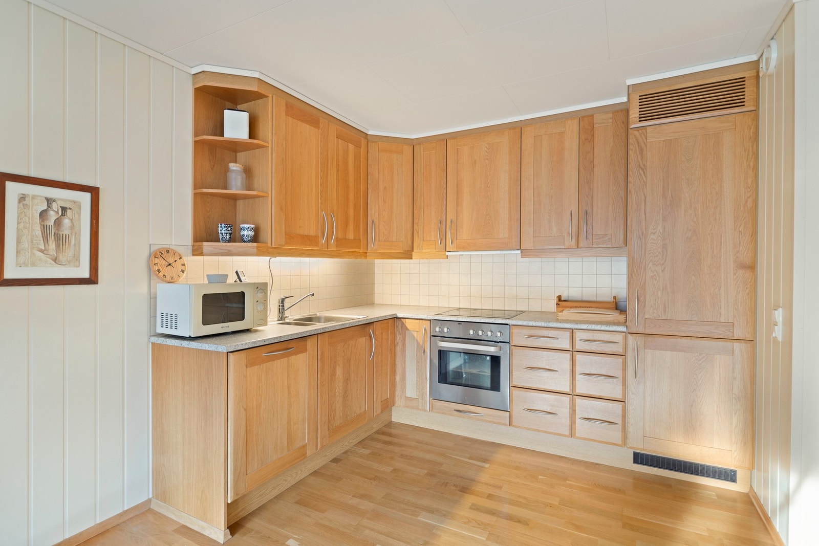 Kjøkkenet har montert en innholdsrik, L-formet innredning fra Møre Kjøkken med benkeskap, høyskap og takhøye overskap Galleribilde