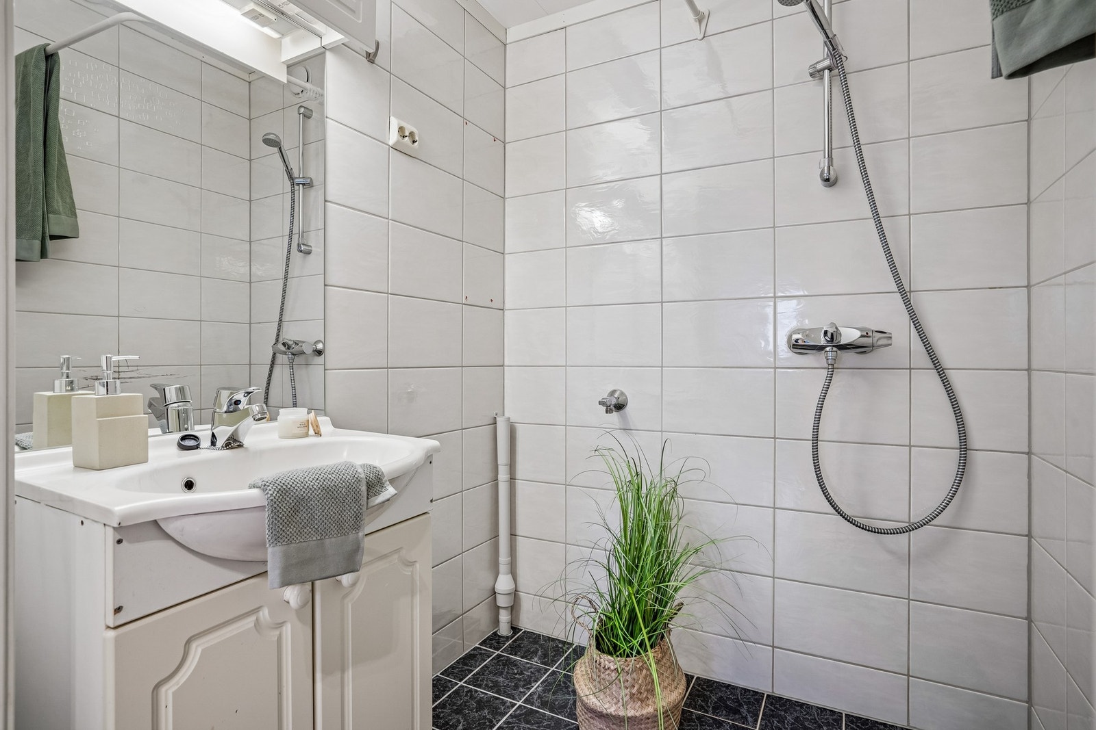 Flislagt bad med lyse farger og opplegg til vaskemaskin. Galleribilde