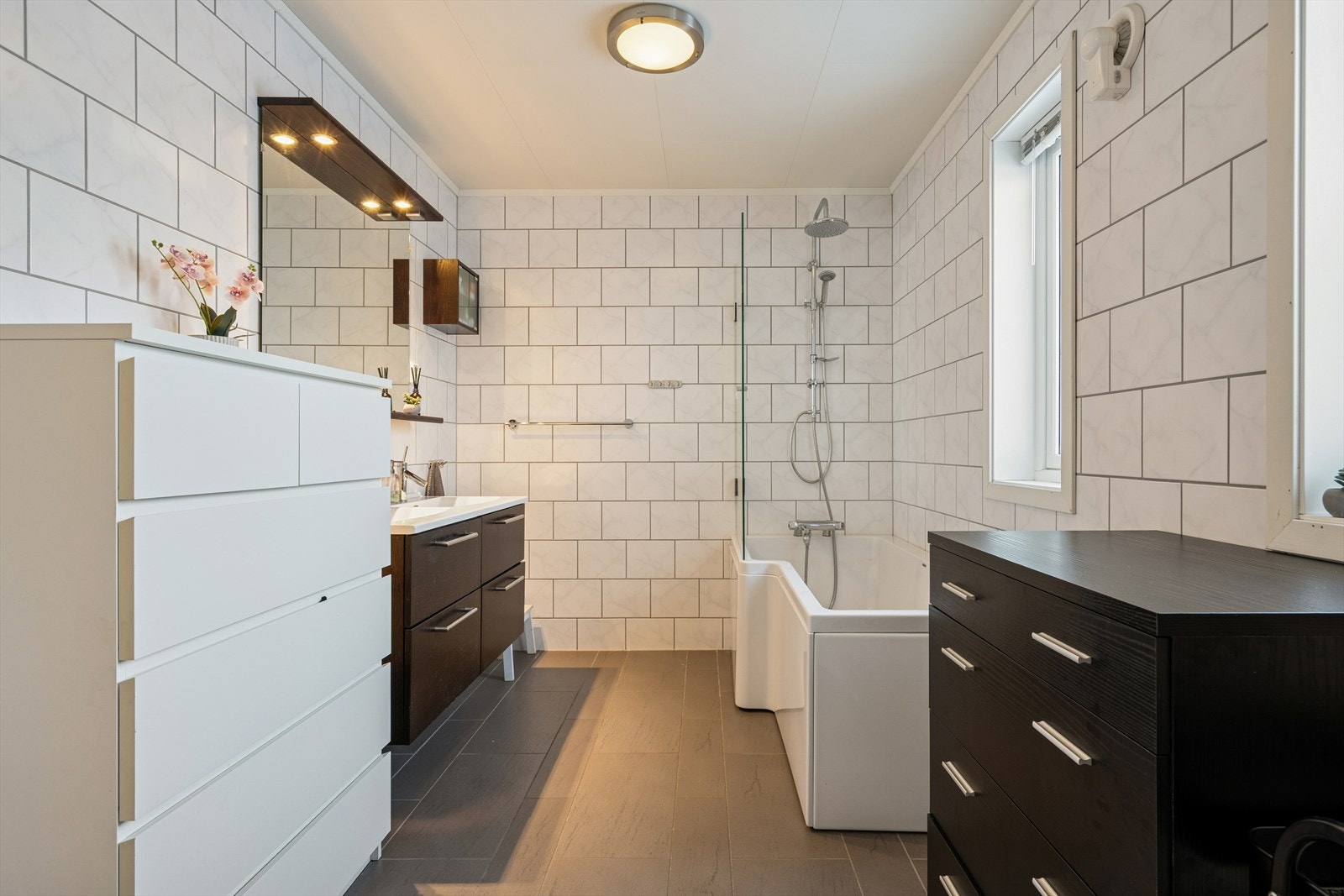 Her finner du badekar m/dusjgarnityr, toalett og baderomsinnredning - Innredningen har to nedfelte servanter som gir rikelig med benkeplass og gjør morgenrutinene mer effektive Galleribilde