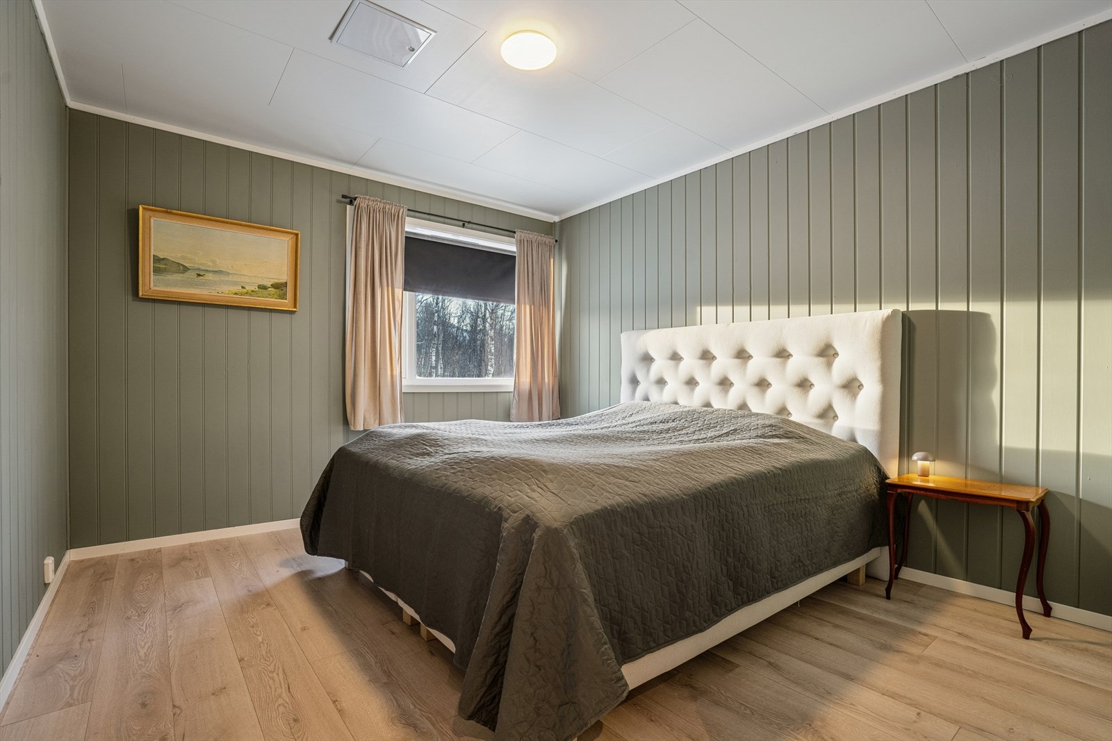 Soverom I - Hovedsoverommet er malt i en lun grønntone og byr på god plass til dobbeltseng med tilhørende nattbord Galleribilde