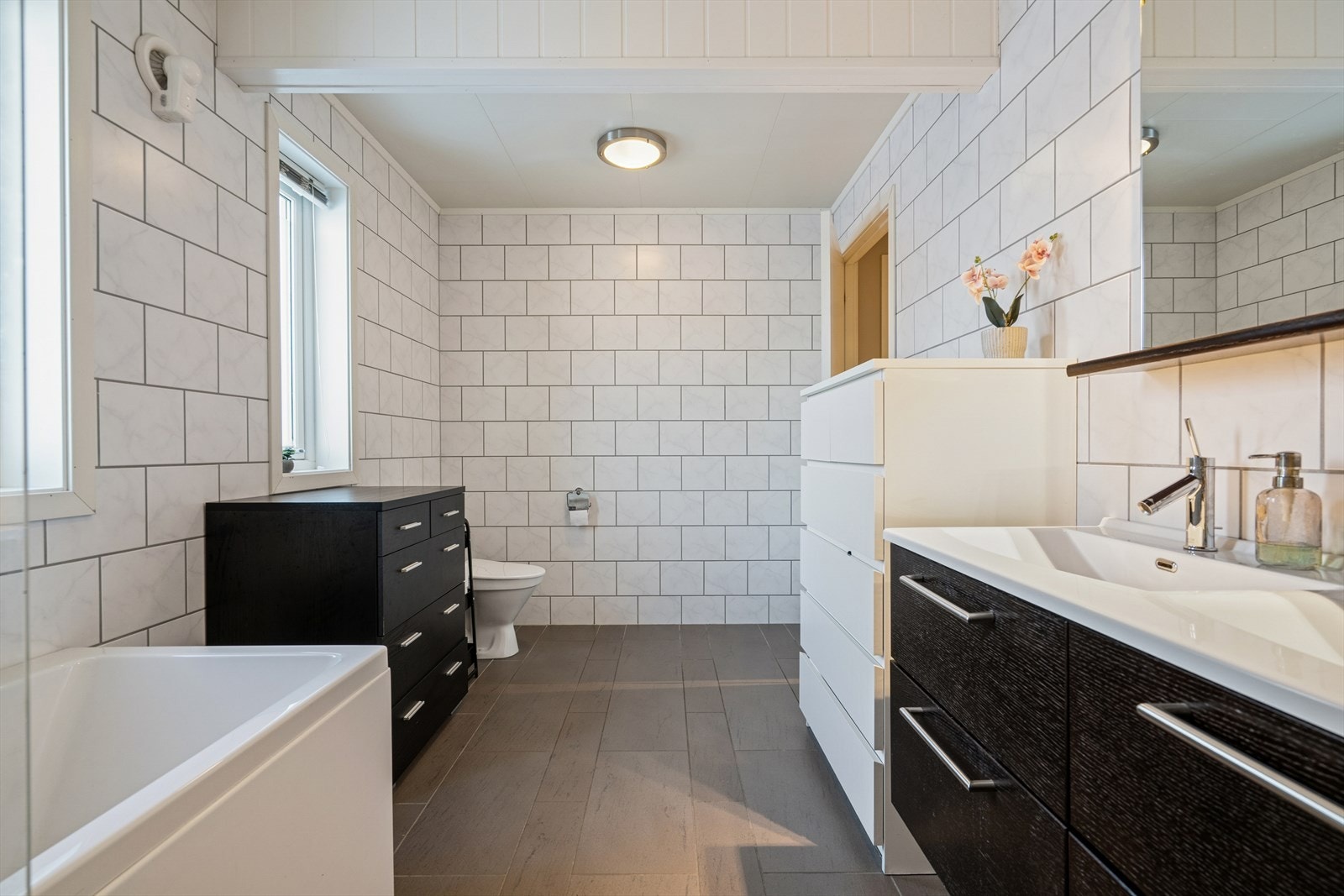 Badet er har flislagte overflater i tidløse farger, noe som gir et helhetlig og tidløst uttrykk - Det er varmekabler i gulvet som sørger for behagelig komfort året rundt Galleribilde