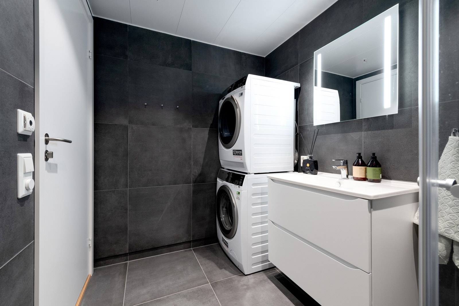 Flott flislagt bad med gulvvarme og opplegg for vaskemaskin og tørketrommel tilknyttet hovedsoverom Galleribilde