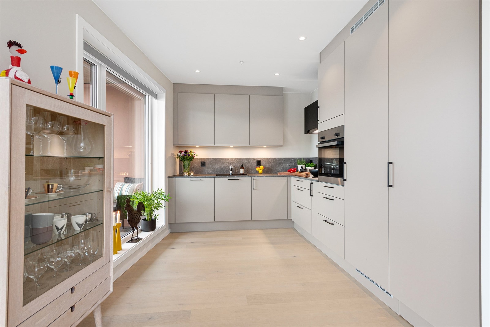 Lyst og fin kjøkkeninnredning med glatte fronter med benkeskapsbelysning Galleribilde