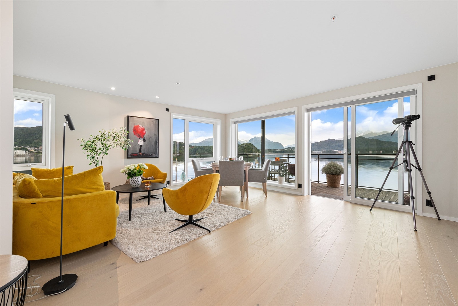 Lys og romslig stue med store vindusflater og en fantastisk utsikt mot fjord og fjell - Foto: Stian Wiik Galleribilde