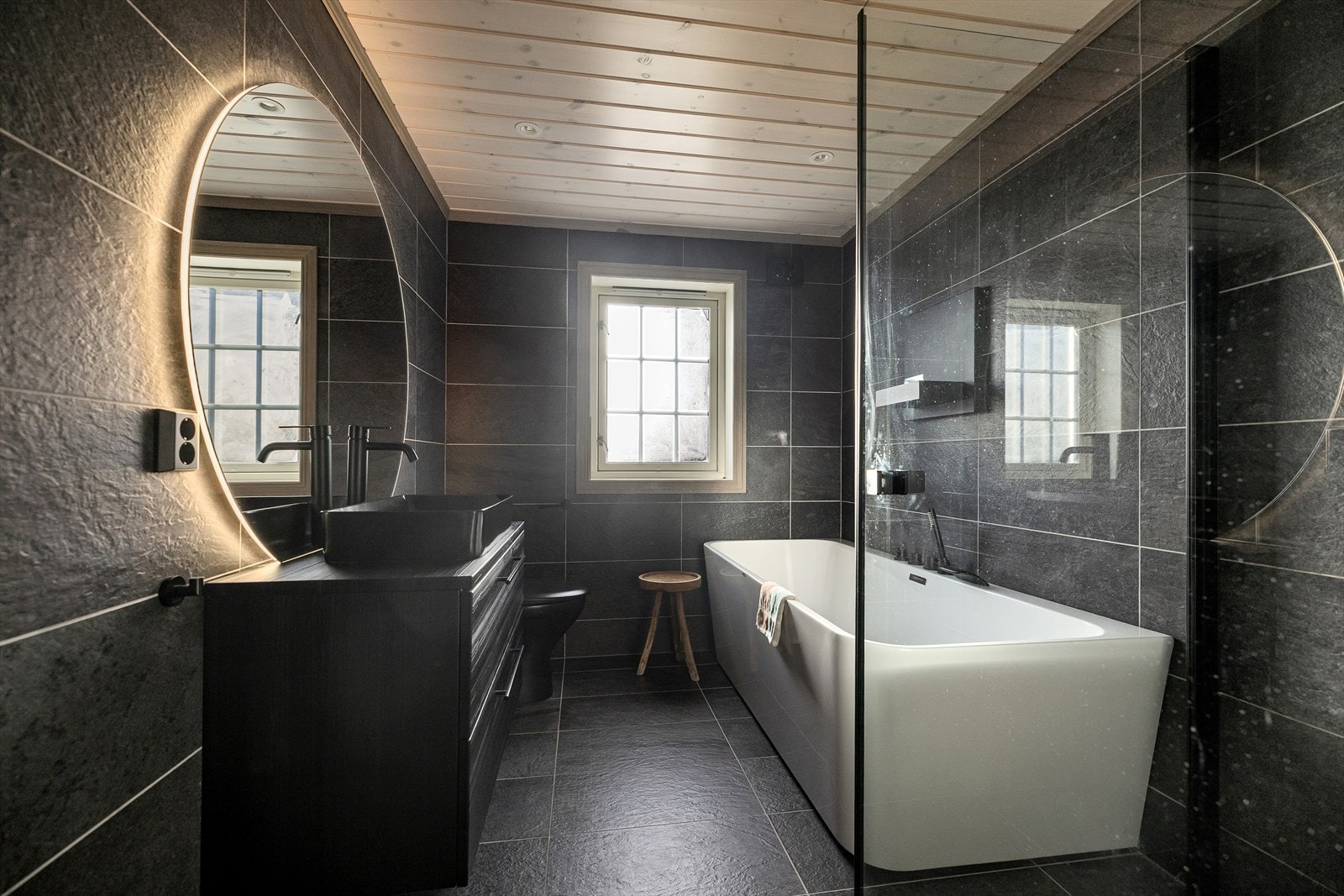 Baderom nr. 2 er også romslig og innbydende, med samme mørke skifrer fliser på gulv og vegger, samt varmekabler i gulvet. Galleribilde