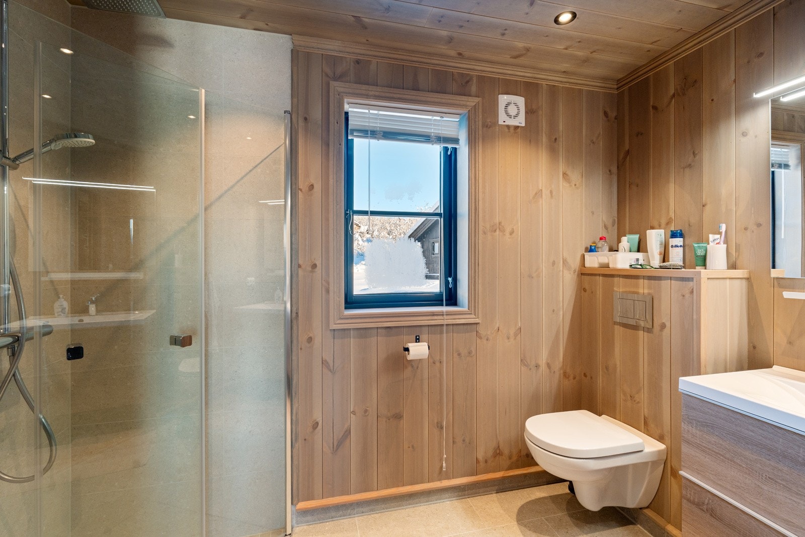 Med adkomst fra hovedsoverommet, ligger det ene badet med høy standard og gode materialvalg. Her er det flislagt gulv med varmekabler, dusjnisje med lokalt fall til sluk, veggmontert toalett og servantinnredning Galleribilde