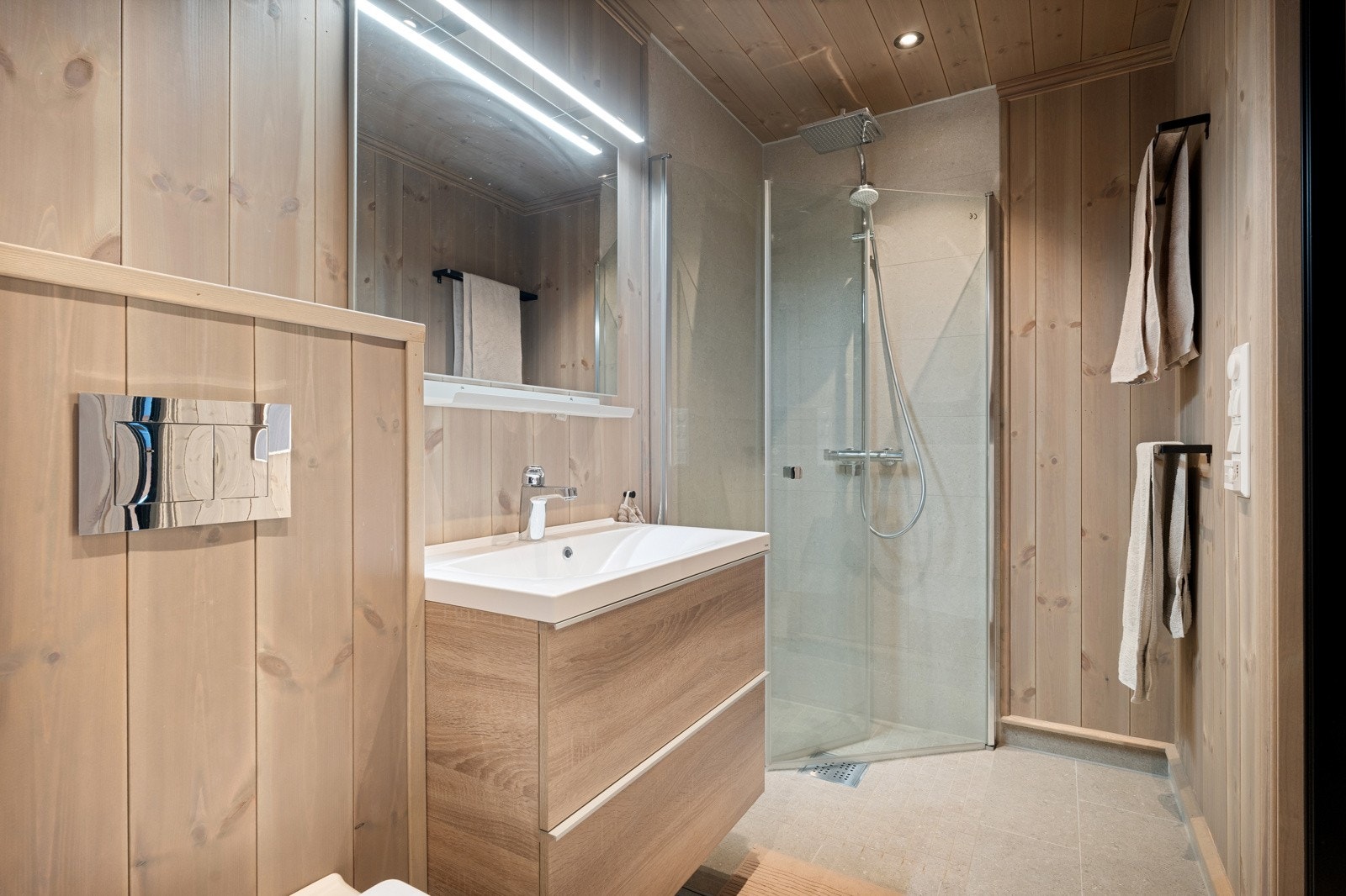 Badet har dusjnisje, veggmontert toalett med innebygd sisterne samt servant med skapinnredning og helstøpt servant. Rommet er ventilert med mekanisk avtrekk. Galleribilde