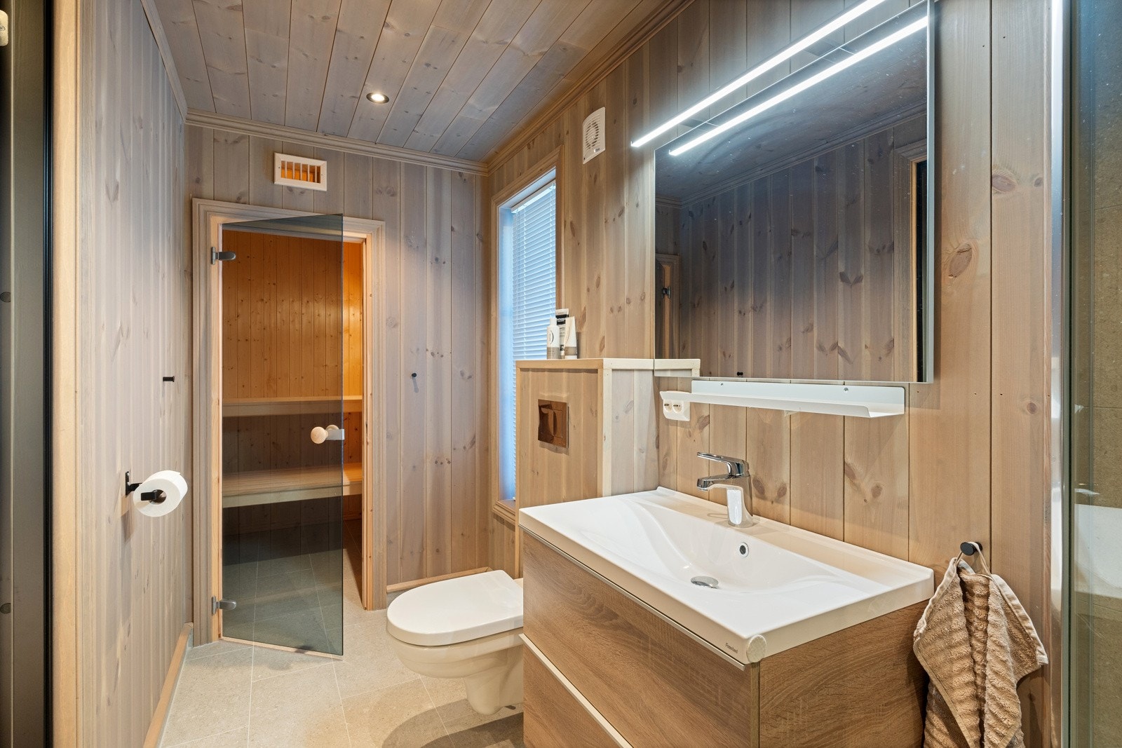 Det andre badet har adkomst fra gang og er innredet med flislagte gulv med varmekabler, fliser på vegger i dusj sone og beiset trepanel på øvrige vegger og i himling Galleribilde