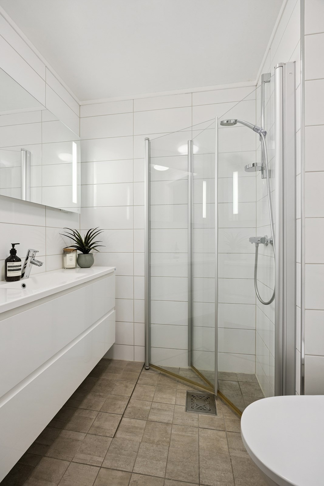 Dusj med innfellbare dører i herdet glass, servant i helstøpt plate og gulvstående klosett. Galleribilde