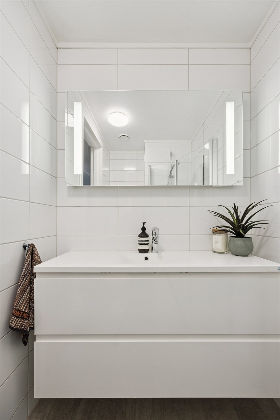 Baderomsinnredningen består av benkeskap med glatte fronter og speil på vegg over servant. Galleribilde