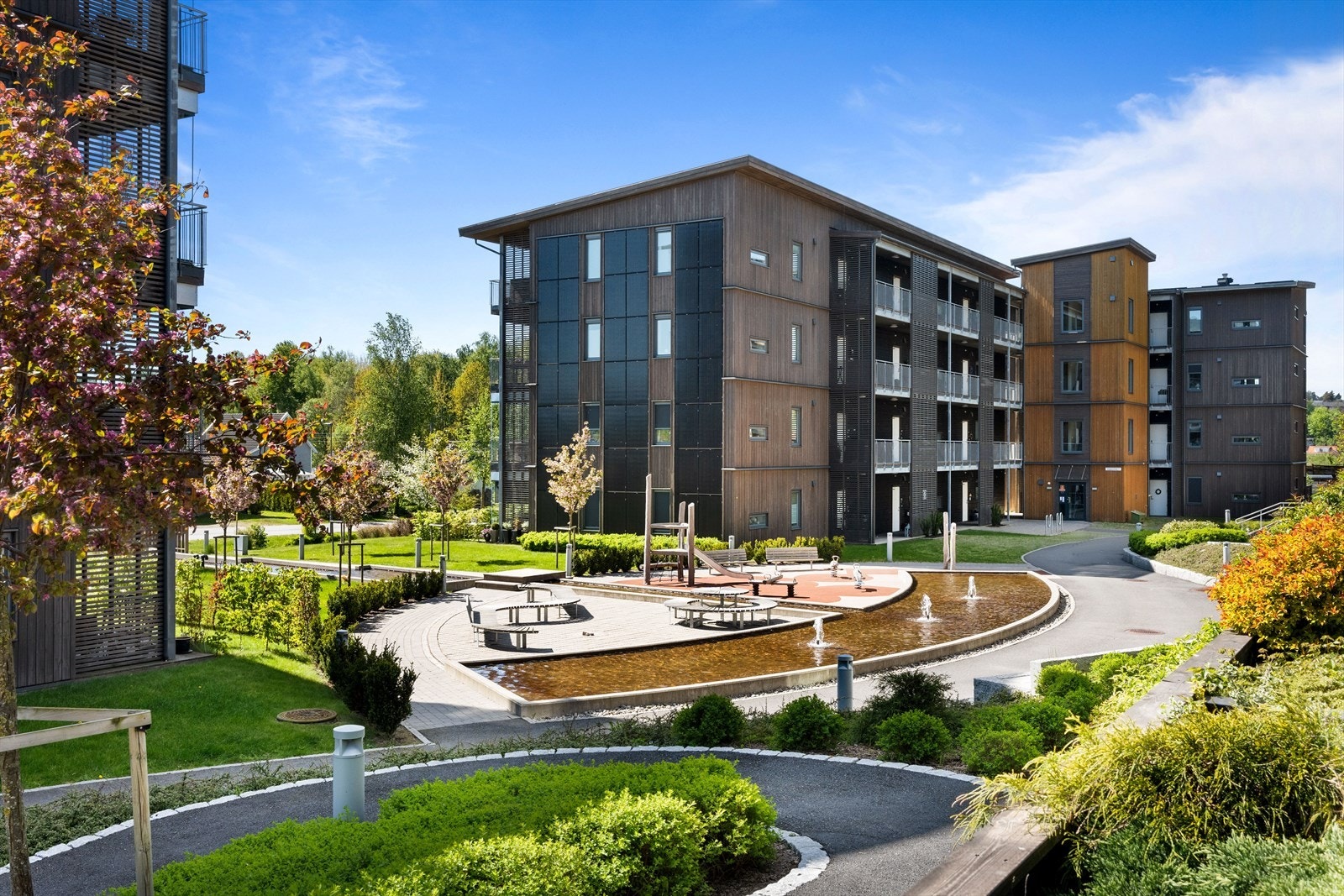 Et innbydende parkanlegg med vannspeil, fontener og sittegrupper. Galleribilde