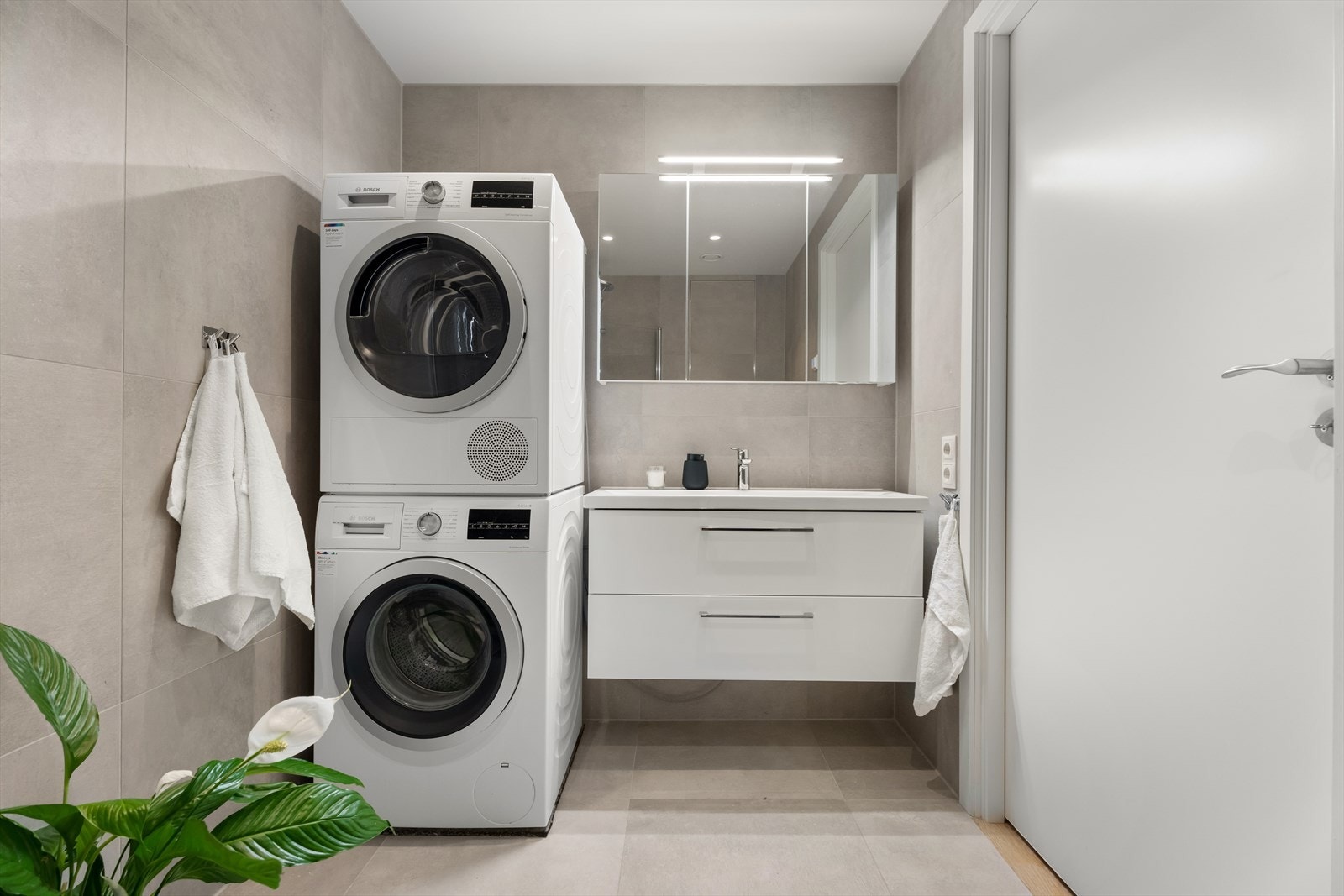 Innredningen inkluderer servantmøbel, speilskap og opplegg for vaskesøyle. Galleribilde