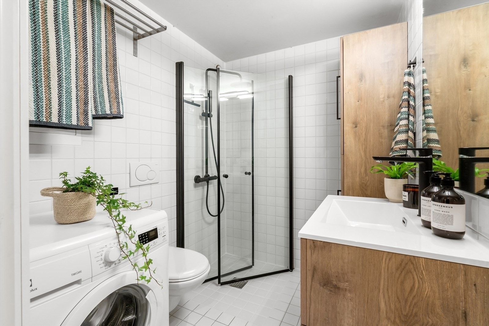 Badet er utstyrt med moderne innredning med nedfelt servant, veggmontert toalett og dusjløsning med vegger i hjørne Galleribilde