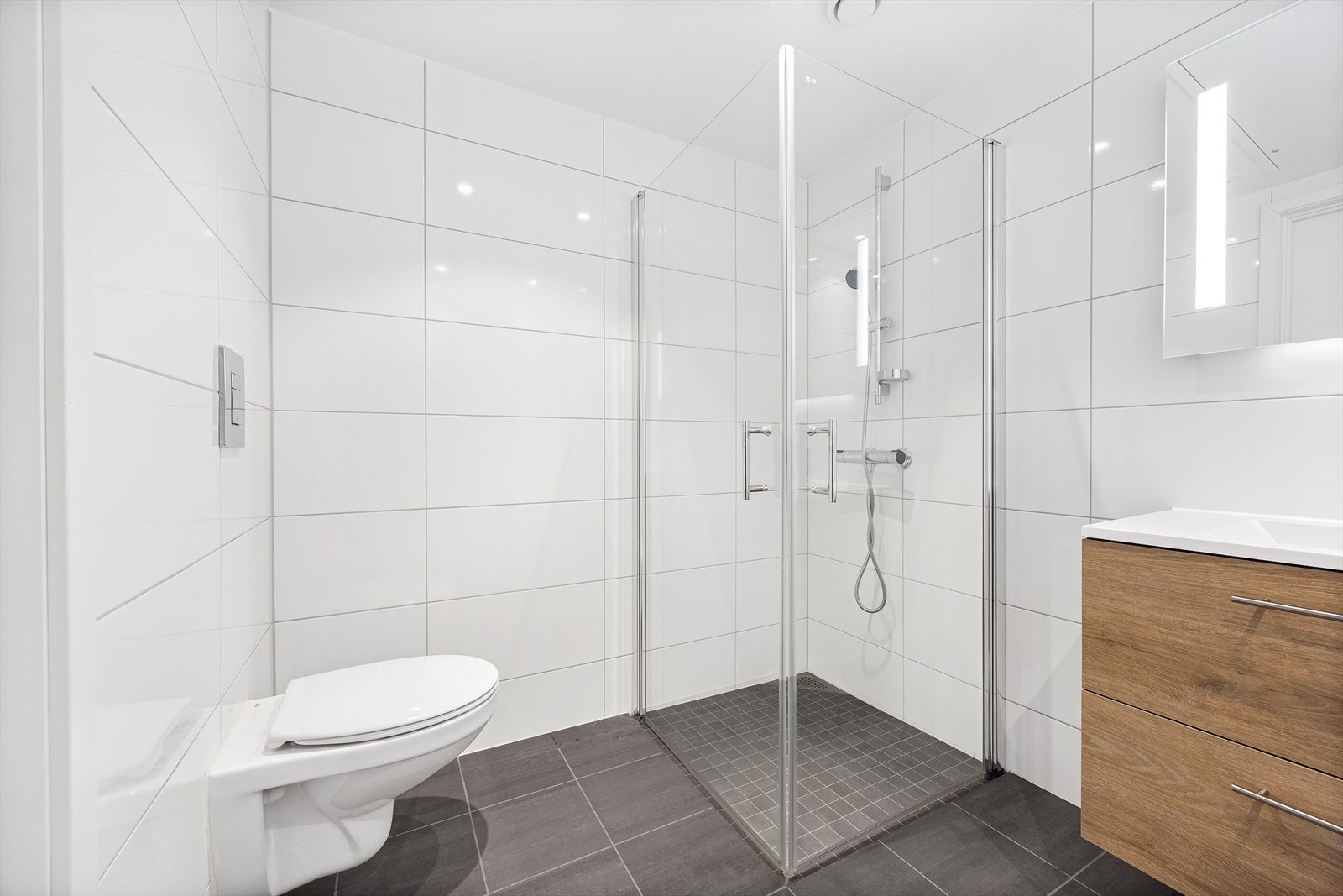 Leiligheten har et tidsriktig baderom med flislagte flater og downlights i taket Galleribilde