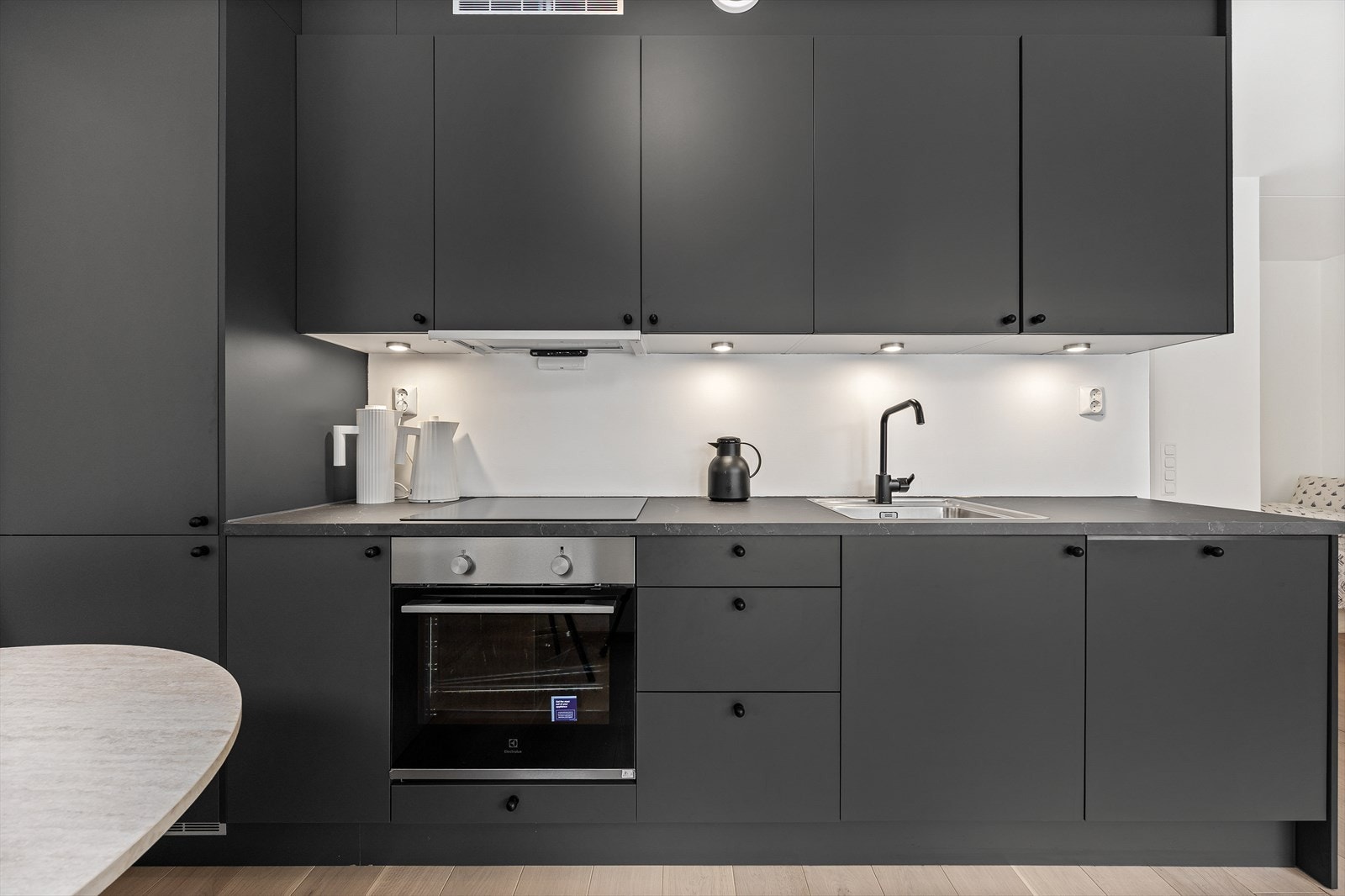 Kjøkkeninnredningen fra Norema har et stilrent utseende med sorte fronter og benkeplate i laminat Galleribilde