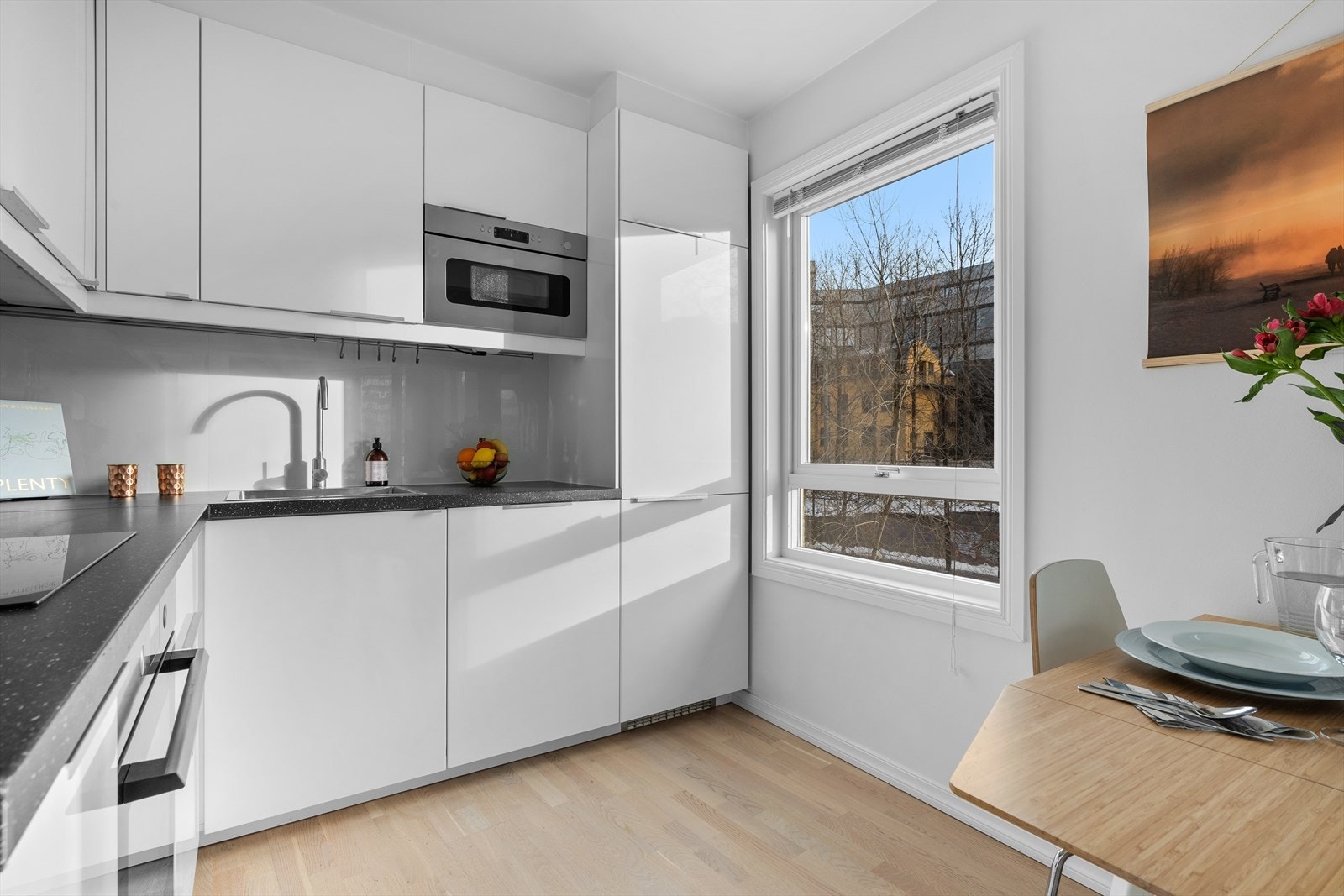 Innredning med glatte, folierte fronter. Laminat benkeplate med nedfelt kum i rustfritt stål. Ledlys under overskap. Galleribilde