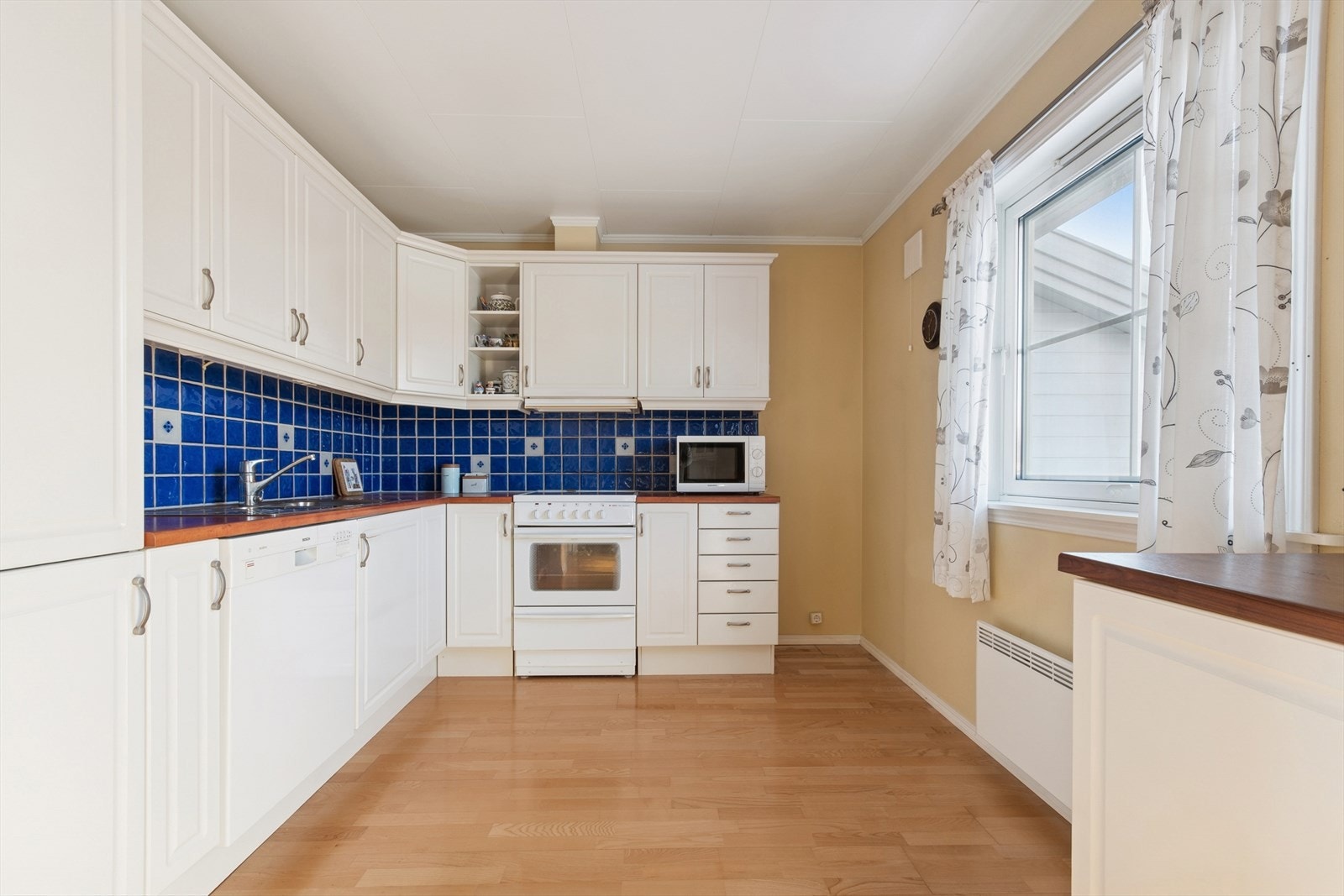 Lys og tidløs innredning med hvite profilerte fronter og benkeplate av typen laminat. Galleribilde