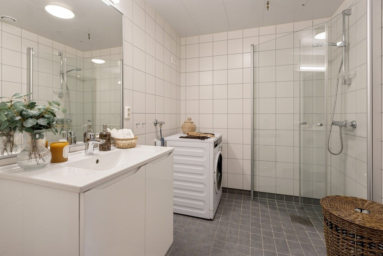 Flislagt bad med dusjhjørne og opplegg for vaskemaskin. Galleribilde