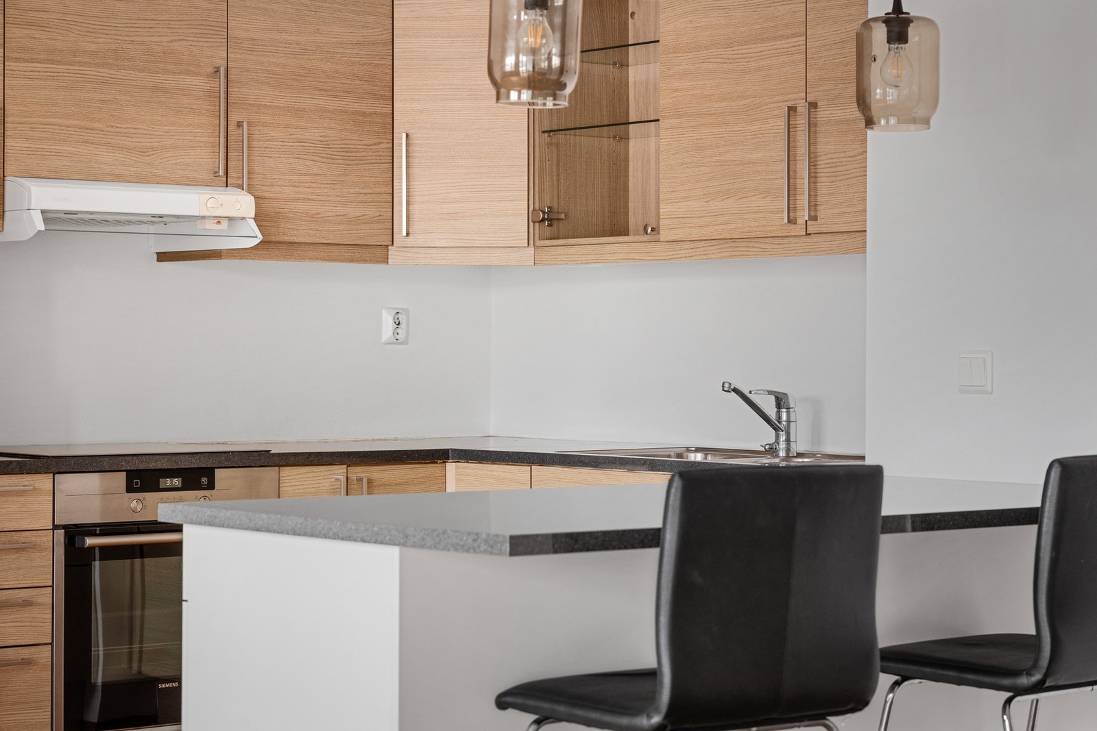 Kjøkkenet fremstår tidløst med slette fronter og laminert benkeplate Galleribilde