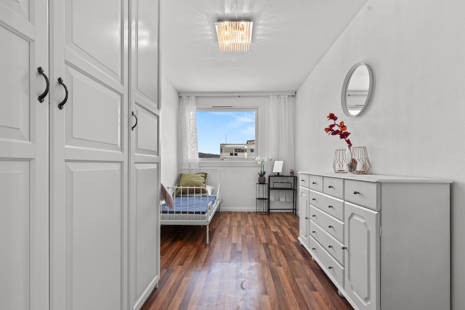 Lyst og romslig soverom med god plass til seng og oppbevaring. Store garderobeskap og kommode gir praktiske løsninger, mens vinduet slipper inn rikelig med naturlig lys. Galleribilde