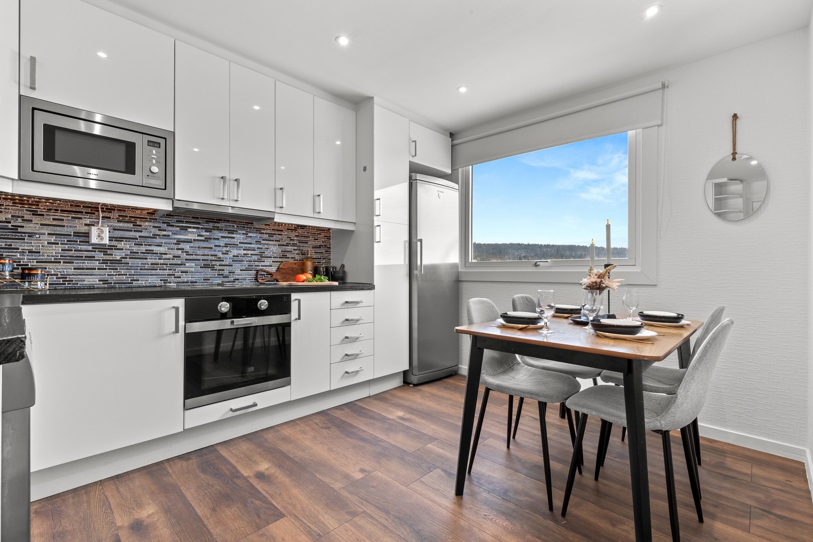 Lyst og innbydende kjøkken med spiseplass ved vinduet og flott utsyn. Her kombineres moderne uttrykk med en hyggelig atmosfære. Galleribilde