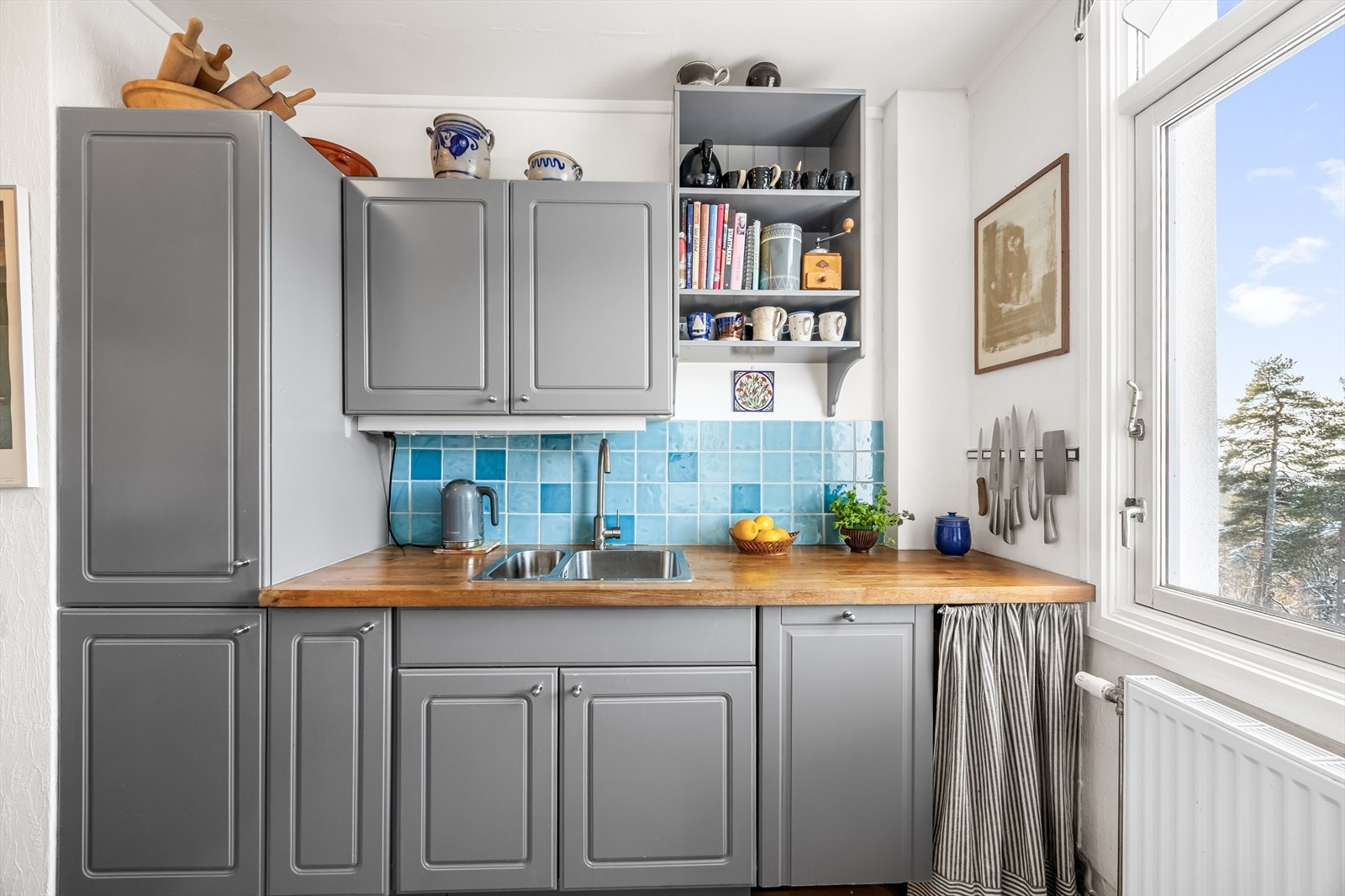 Fliser over kjøkkenbenken og åpne hyller gir rommet et personlig preg. Galleribilde