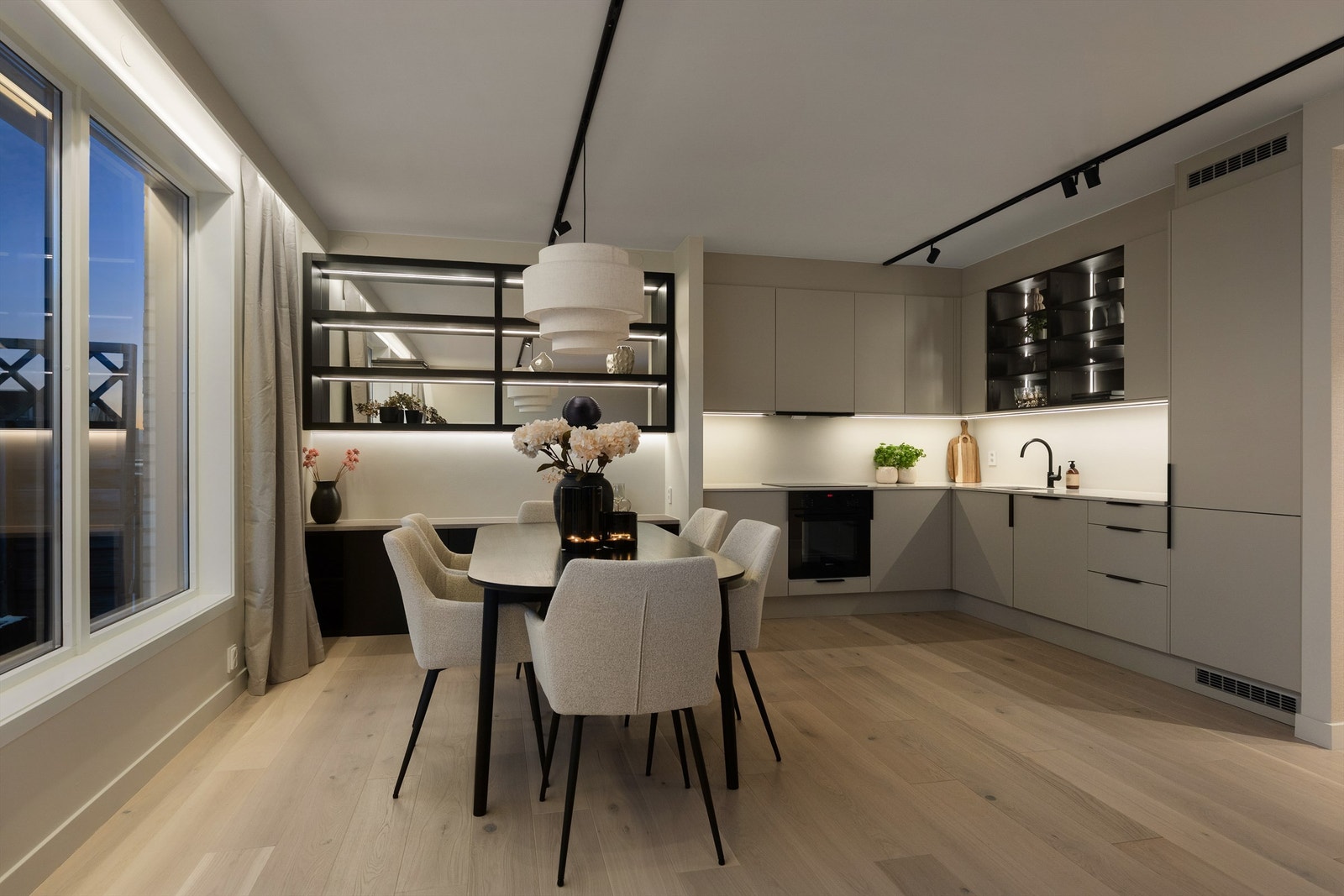 Selv om kjøkkenet og spisestuen ligger åpent mot hverandre, føles det som separate soner takket være både belysning og de vakre speilskapene. Galleribilde