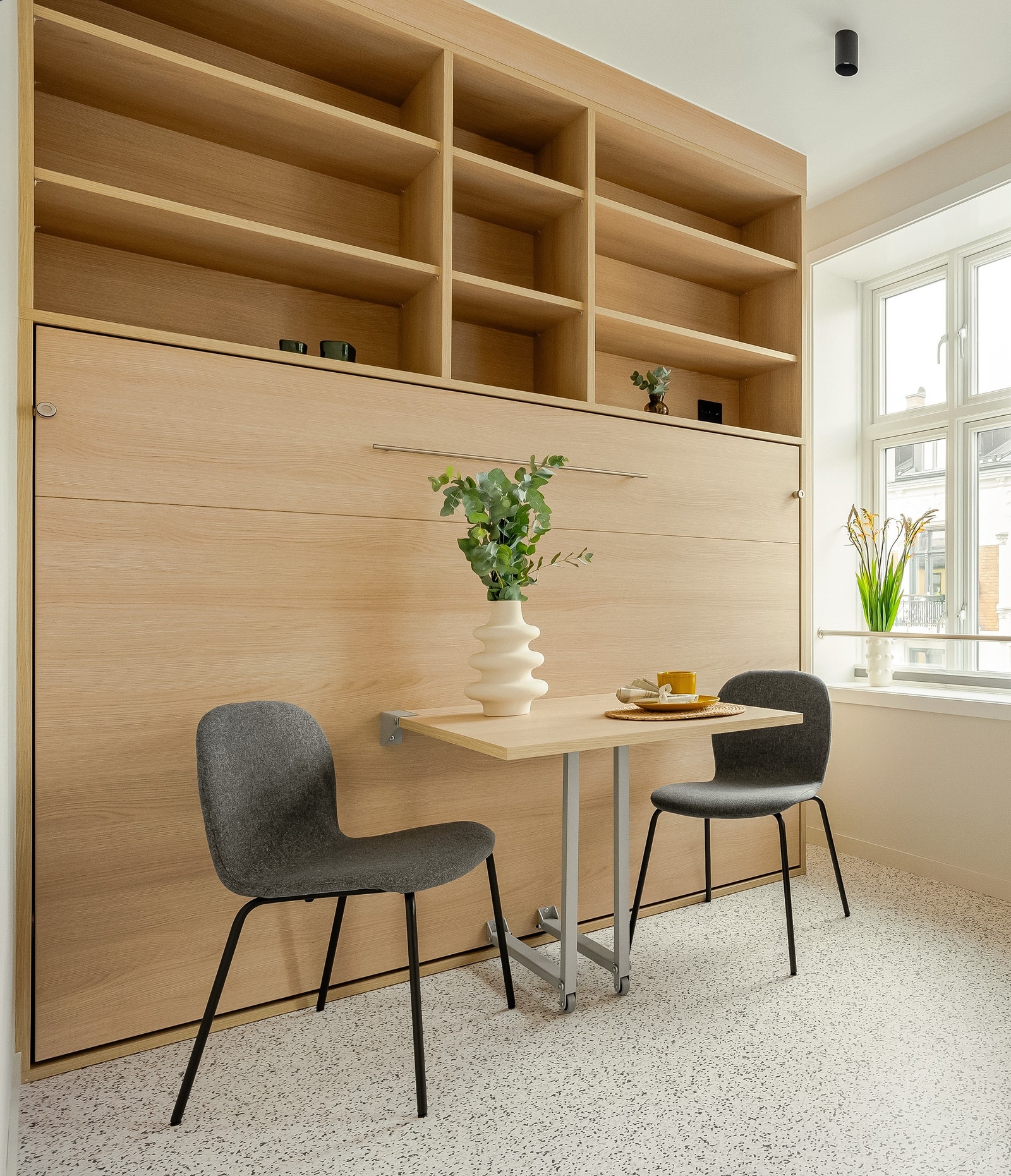 Bilde fra tilsvarende leilighet viser hvordan sengen sjules i hylle bak bordet Galleribilde